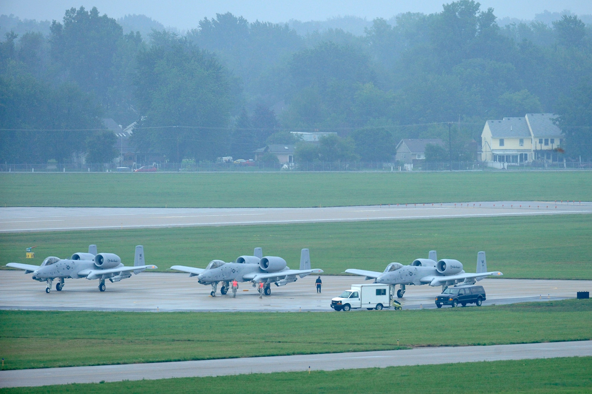 Ground crew personnel perform the final maintenance checks and adjustments as three A-10 Thunderbolt II aircraft wait at the “last chance” holding area just prior to take off in an early morning rain at Selfridge Air National Guard Base, Mich., Aug. 10, 2012. Airmen from the 107th Fighter Squadron, who fly the aircraft, and the 127th Maintenance Group, who maintain the aircraft, participated in a surge operation, launching and recovering a higher-than-usual number of aircraft, as part of a series of readiness training exercises taking place at the base in August. (Air National Guard photo by John S. Swanson)