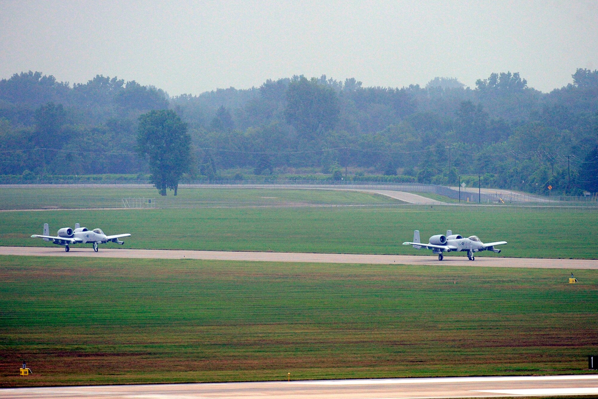 Two A-10 Thunderbolt II aircraft prepare to take-off during a light rain at Selfridge Air National Guard Base, Mich., Aug. 10, 2012. Airmen from the 107th Fighter Squadron, who fly the aircraft, and the 127th Maintenance Group, who maintain the aircraft, participated in a surge operation, launching and recovering a higher-than-usual number of aircraft, as part of a series of readiness training exercises taking place at the base in August. (Air National Guard photo by John S. Swanson)