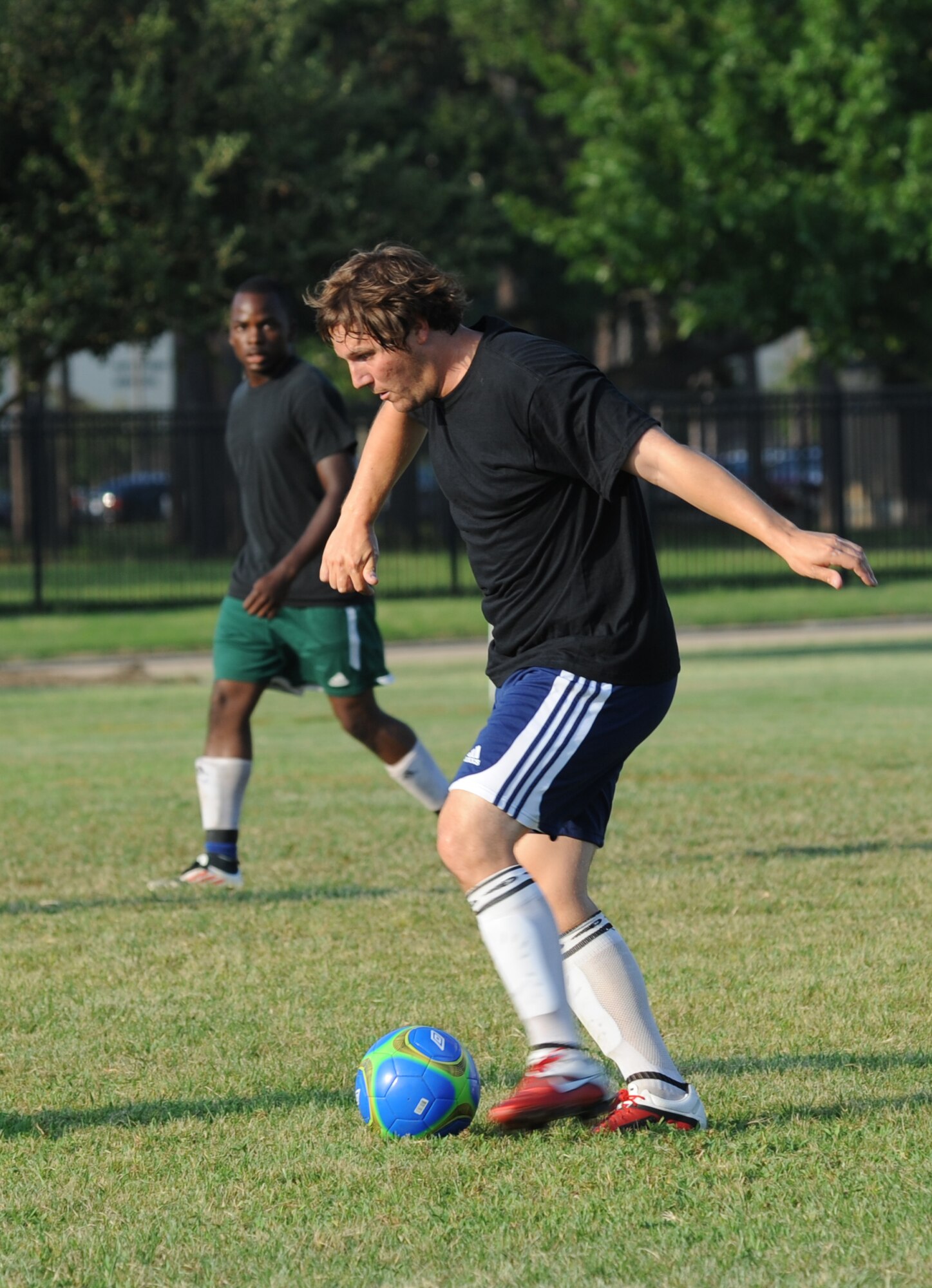 Rajab Kigembe, 85th Engineering Installation Squadron, keeps a watchful eye on his teammate, William Boxx, as he dribbles the soccer ball down the field during an intramural soccer game against the 334th Training Squadron August 7, 2012, at Keesler Air Force Base, Miss.  The Gators defeated the 85th 6-2.  (U.S. Air Force photo by Kemberly Groue)