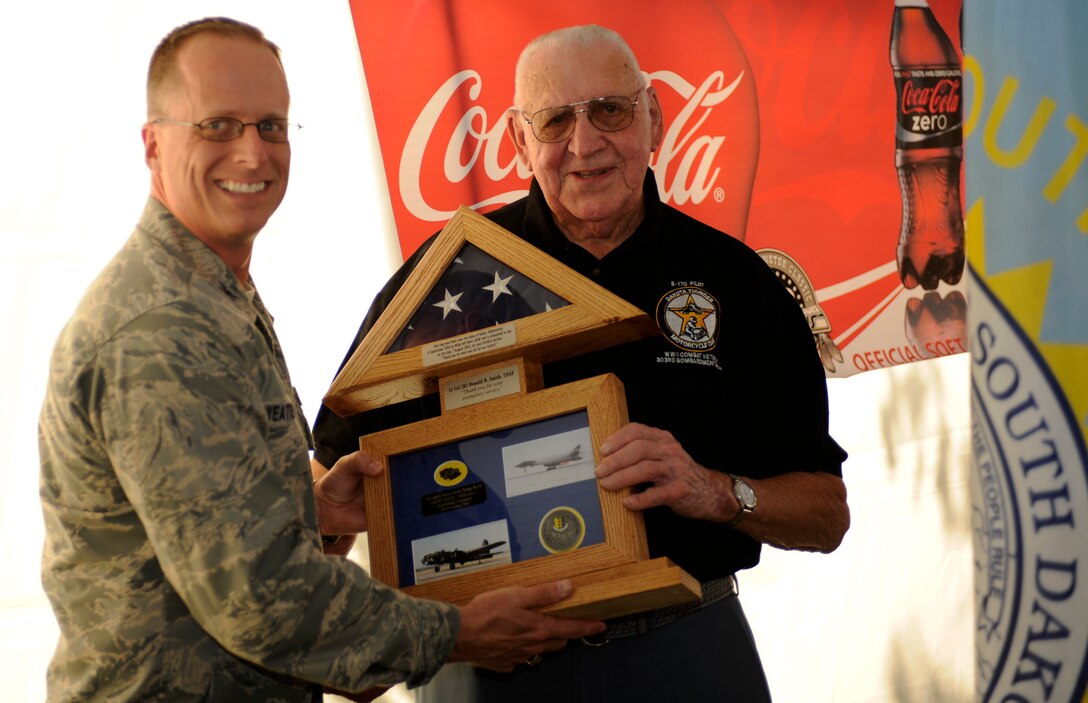 Col. Mark Weatherington, 28th Bomb Wing commander, presents retired Lt. Col. Donald Smith with an American flag that was flown over Afghanistan by a B-1 from Ellsworth on the 10th anniversary of 9/11 during a Military Appreciation Day event in Sturgis, S.D., Aug. 7, 2012. In addition to the flag, the shadow box also contained a piece of 88mm shell that blew Smith?s left rudder pedal off during one of his combat missions over Germany as a B-17 co-pilot. (U.S. Air Force photo by Airman Ashley J. Cass/Released) 