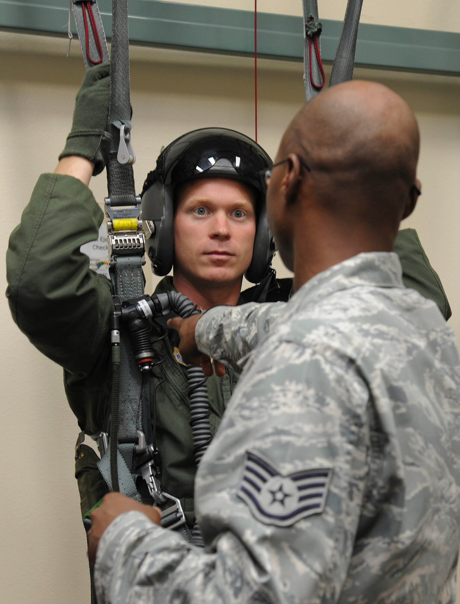 Staff Sgt. Branden Rowe, 56th Operations Support Squadron Aircrew Flight Equipment continuation trainer, assists Capt. Patrick Kennedy, 309th Fighter Squadron weapons and tactics chief, into the post-ejection hanger. The post-ejection hanger acquaints the pilot with the sensation of hanging from a parachute.. (U.S. Air Force photo by Staff Sgt. Darlene Seltmann)