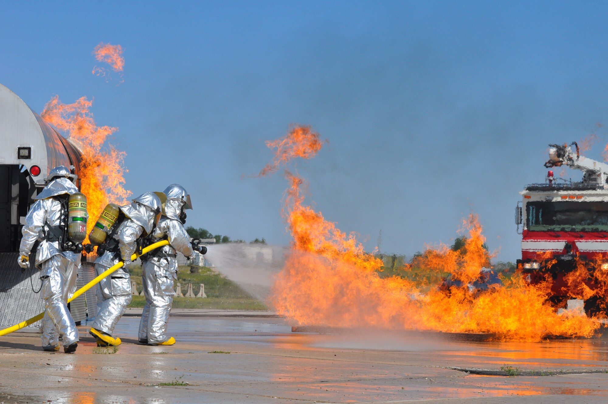 Firefighters from the 90th Civil Engineer Squadron battle a wall of fire before moving to a fire on the side of a Mobile Air Fire Trainer during an annual training exercise Aug 3 at the Wyoming Air National Guard. The firefighters have used the trainer to meet their annual training requirements for Air Force and Federal Aviation Association firefighters since its arrival in Cheyenne in June. (U.S. Air Force photo by Senior Airman Dan Gage)
