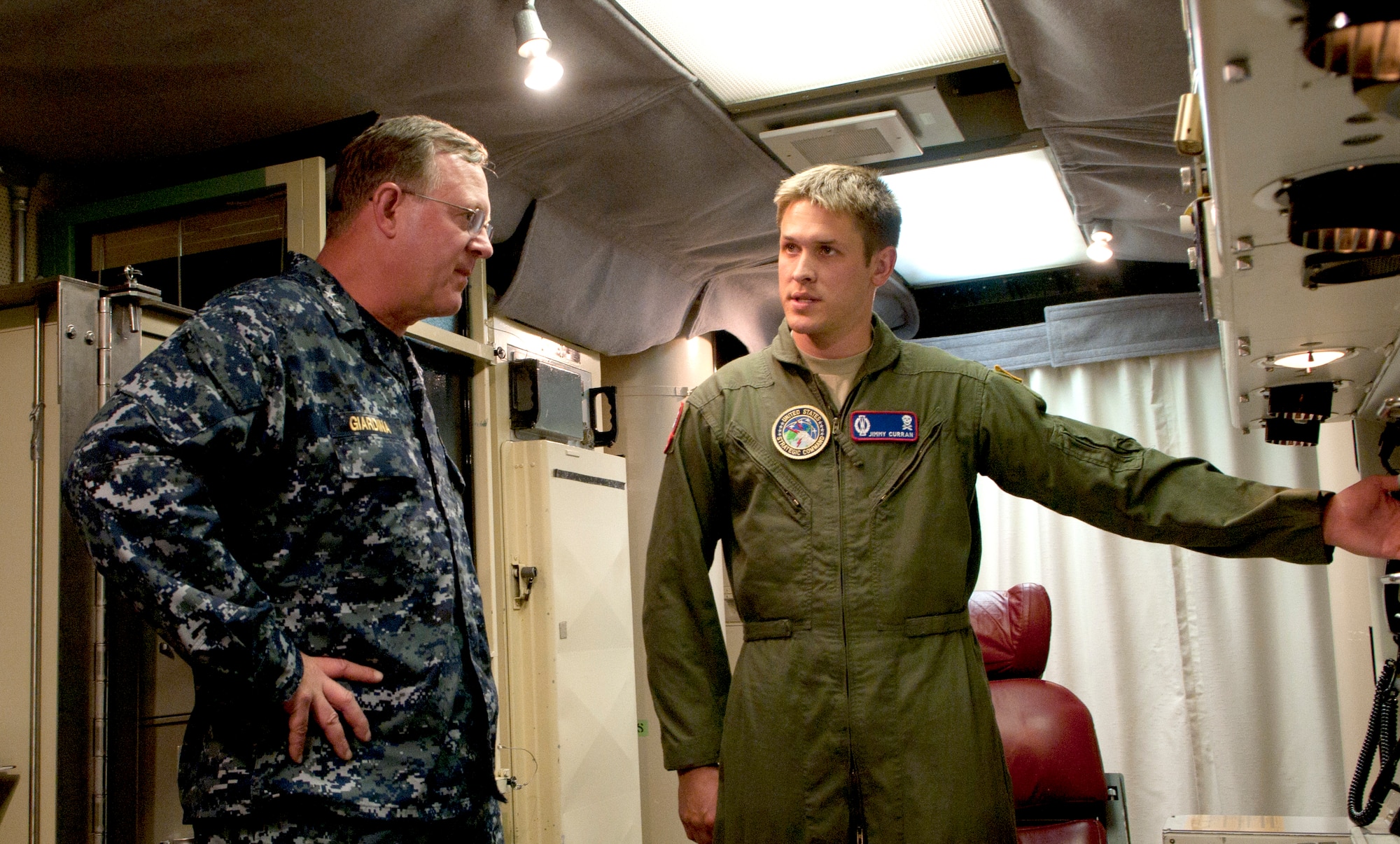 1st Lt. Jimmy Curran, 319th Missile Squadron crew commander, explains his job procedures and use of the control panel in the launch control center of a missile alert facility and answers questions from Navy Vice Adm. Timothy M. Giardina, U.S. Strategic Command deputy commander, July 31. (U.S. Air Force photo by Airman 1st Class Jason Wiese)
