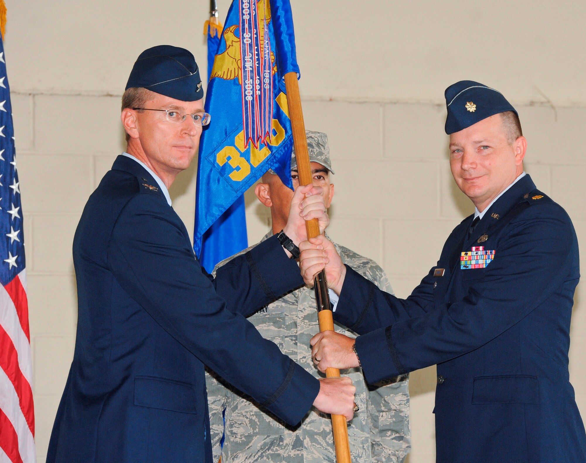 Colonel Curtis Hafer (Left), 325th Maintenance Group commander, passes the 325th Maintenance Squadron guidon to Maj. Shawnn Martin (Right) who assumed command of the 325th MXS in a change of command ceremony Aug. 10. (U.S. Air Force photo by Christopher Cokeing) 