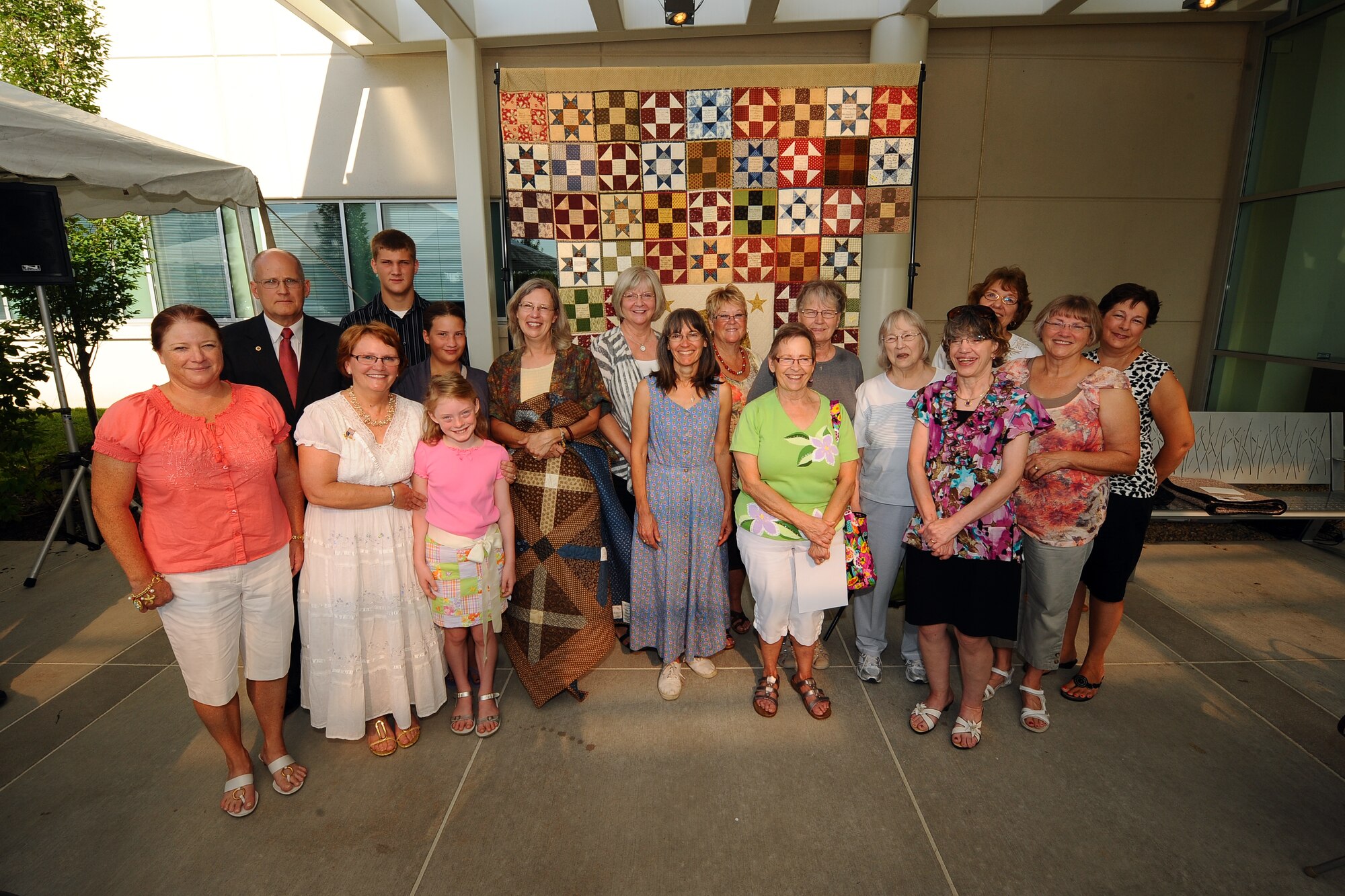 The members of the Home of the Brave quilt project stand with Petty Officer 1st Class Caleb A. Nelson’s family who received the quilt in his honor at a ceremony held at the Bellevue Medical Center, in Bellevue, Neb., Aug. 7.  Local area quilters each added a single square to the quilt to give to the family.  (U.S. Air Force photo by Josh Plueger/Released)