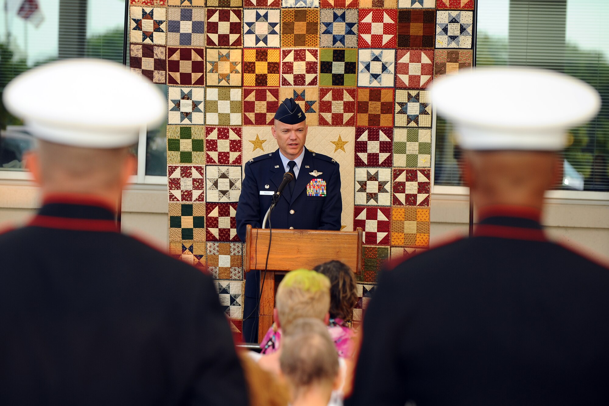 U.S. Air Force Col. John Rauch, 55th Wing commander, addresses the people in attendance at a ceremony to view a traveling memorial depicting those Nebraskans who’ve given all in combat at the Bellevue Medical Center in Bellevue, Neb., Aug. 7.  The unfinished quilt, behind the wing commander, is being put together as part of the Home of the Brave Quilt Project where Nebraskan’s each design a patch to add to the quilt.  (U.S. Air Force photo by Josh Plueger/Released)