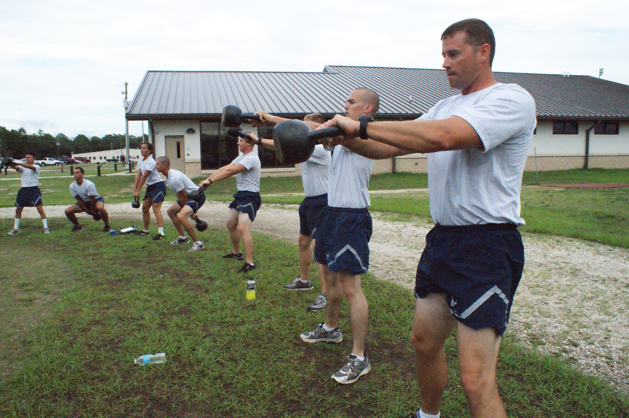 Airmen-in-training at Naval School Explosive Ordnance Disposal do kettlebell swings during Battlefield Survivability through Physical Fitness training July 19, 2012, at Eglin Air Force Base, Fla.  The program,designed by the 366th Training Squadron Field Training Detachment 3 and 96th Force Support Squadron, emphasizes weightlifting mechanics, increased strength, power and agility.  (U.S. Air Force photo/Dan Hawkins)