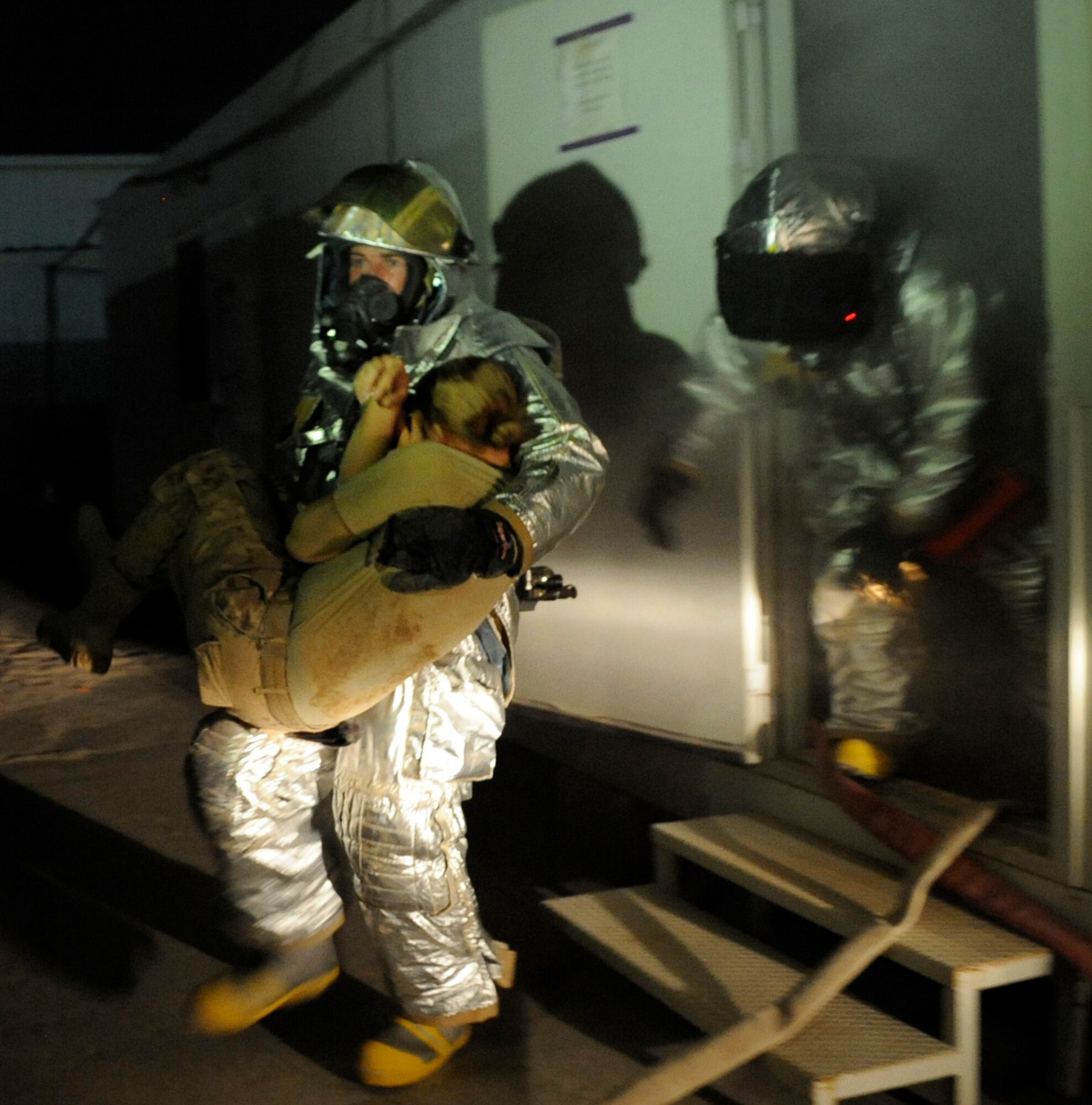 SOUTHWEST ASIA – Staff Sgt. James Michalisko hands a victim off to Staff Sgt. Ryan Leslie, 386th Expeditionary Civil Engineer Squadron fire fighters, during a practical exercise here August 7. The fire department training manager set up the scenario with simulated victims trapped between the vehicle and the building, unconscious and lost in the smoke inside the building. (U.S. Air Force photo/Staff Sgt. Alexandra M. Boutte)