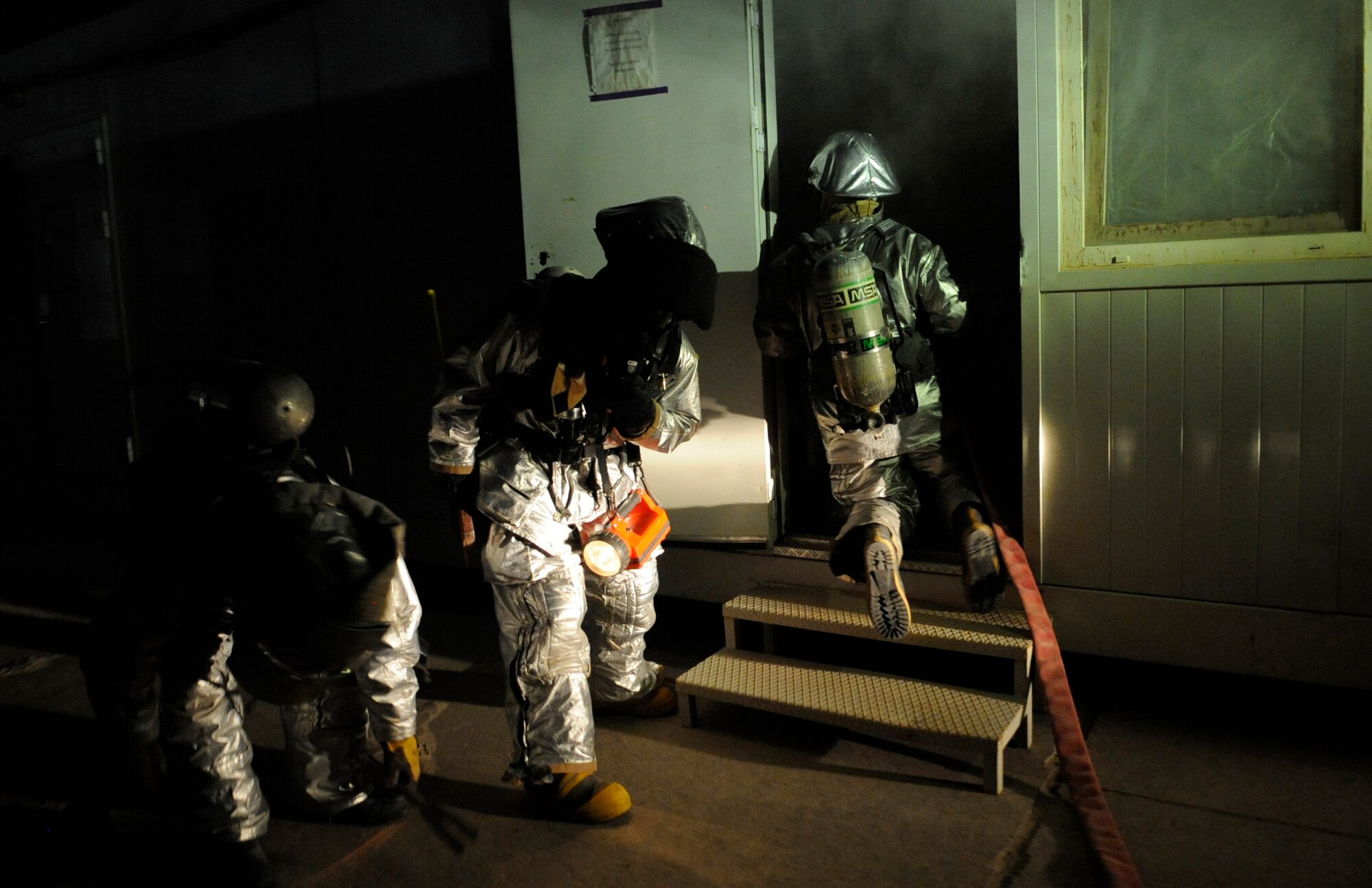 SOUTHWEST ASIA – A rescue team of firefighters from the 386th Expeditionary Civil Engineer Squadron, prepare to enter a building full of smoke to look for potential victims during a practical exercise here August 7. Before entering a smoking building, the fire fighters placed protective equipment on such as the self-contained breathing apparatus, flashlights, pants and coat, gloves and nomex hood to protect the neck and head from the heat. The fire fighters will also bring a tool such as an ax and a halogen bar if there’s a possibility of forcible entry. (U.S. Air Force photo/Staff Sgt. Alexandra M. Boutte)