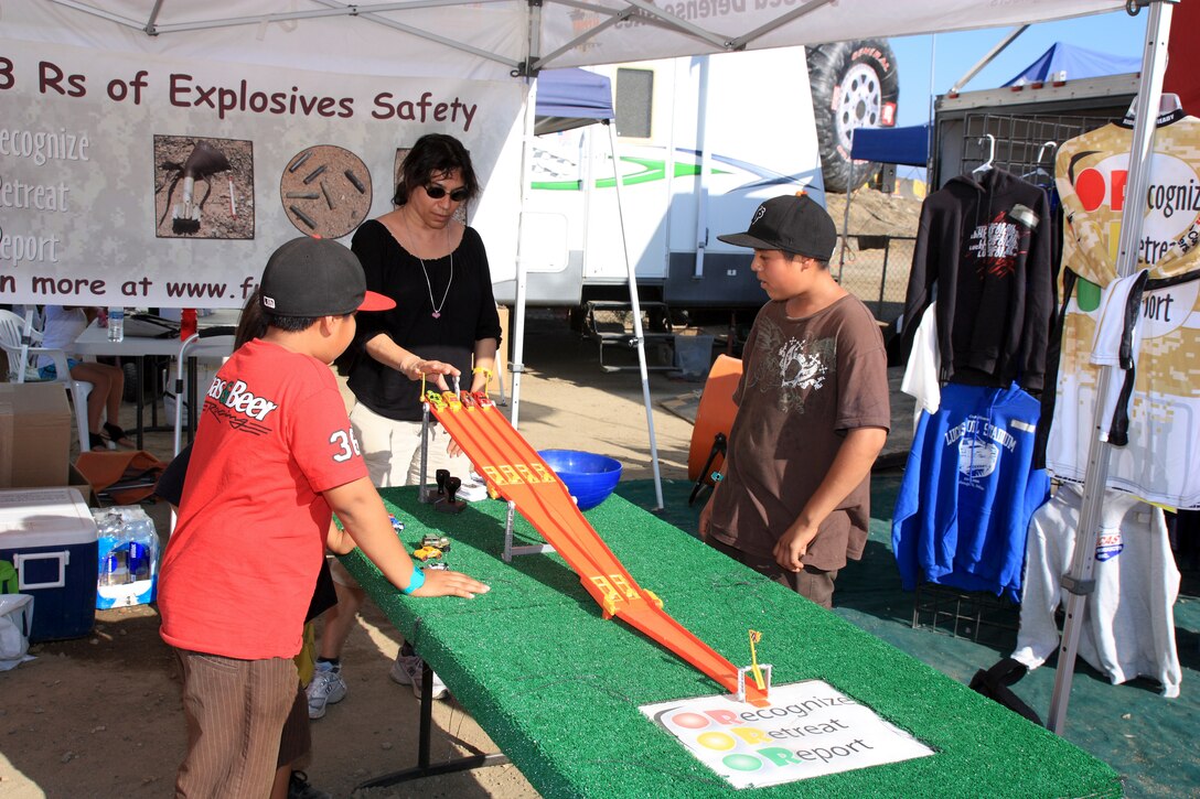 Suneeta Sahgal (center) a Los Angeles District FUDS project manager speaks with young participants about the 3Rs of explosives safety during a Lucas Oil Off Road Racing Series event held at the Glen Helen Raceway in San Bernardino Aug. 4-5. The finish line of the game, fact sheets and prizes reflect the programs key message: Recognize, Retreat and Report.