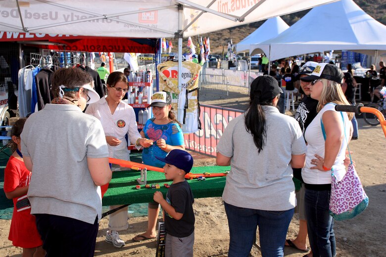 Fran Firouzi (left center) a Los Angeles District FUDS project manager hands a 3Rs of Explosives Safety sticker to a young race fan during a Lucas Oil Off Road Racing Series event held at the Glen Helen Raceway in San Bernardino Aug. 4-5. District program managers and contract partners from Bristol Environmental Remediation Services spoke to off-road fans of all ages during the two-day event.
