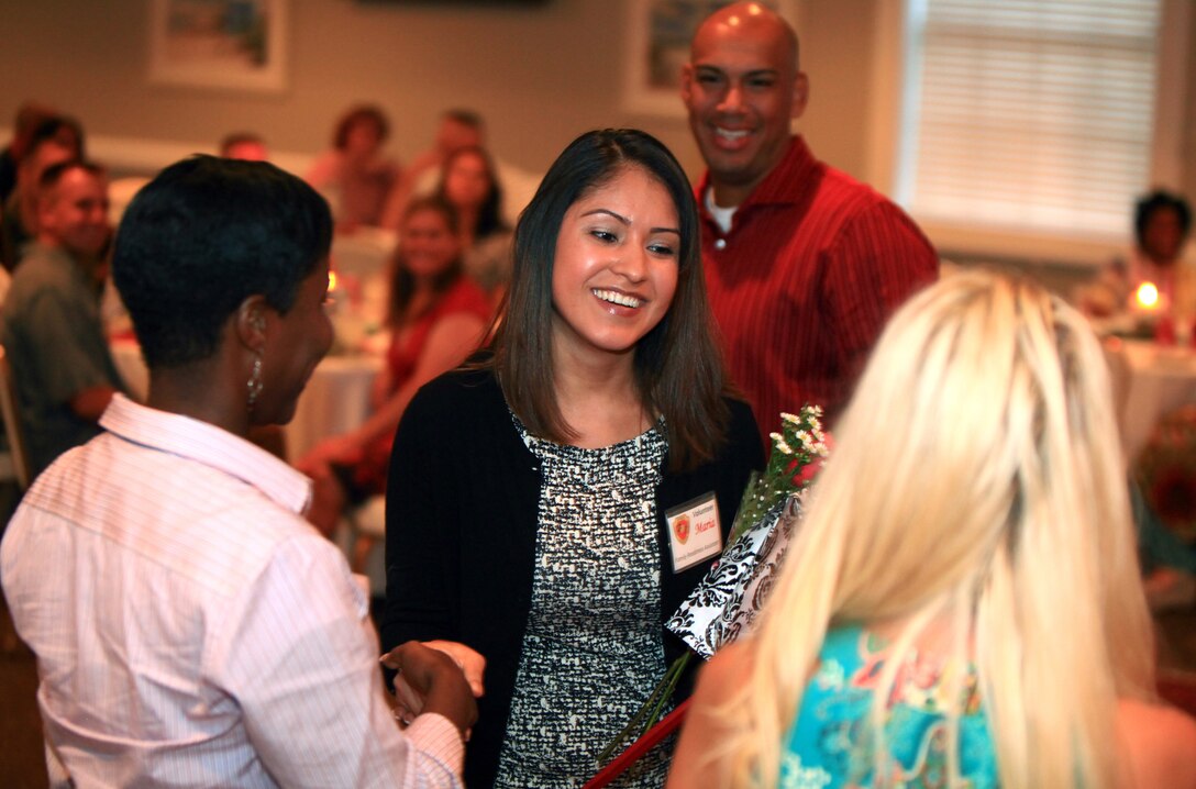 Maria Lopez (middle), wife of 1st Sgt. Jerry Lopez, receives gifts from Kim Hollahan (right), the wife of Combat Logistics Regimental 27 commanding officer, and Sgt. Maj. Lanette Wright (left), the CLR-27 sergeant major, as a small token of appreciation for her support as a volunteer and spouse during a Spouse Appreciation Night at the Ball Center at Camp Lejeune, N.C., Aug. 10, 2012. The gifts included a bag of goodies, a flower and an award signed my Col. Mark R. Hollahan, the CLR-27 commanding officer.