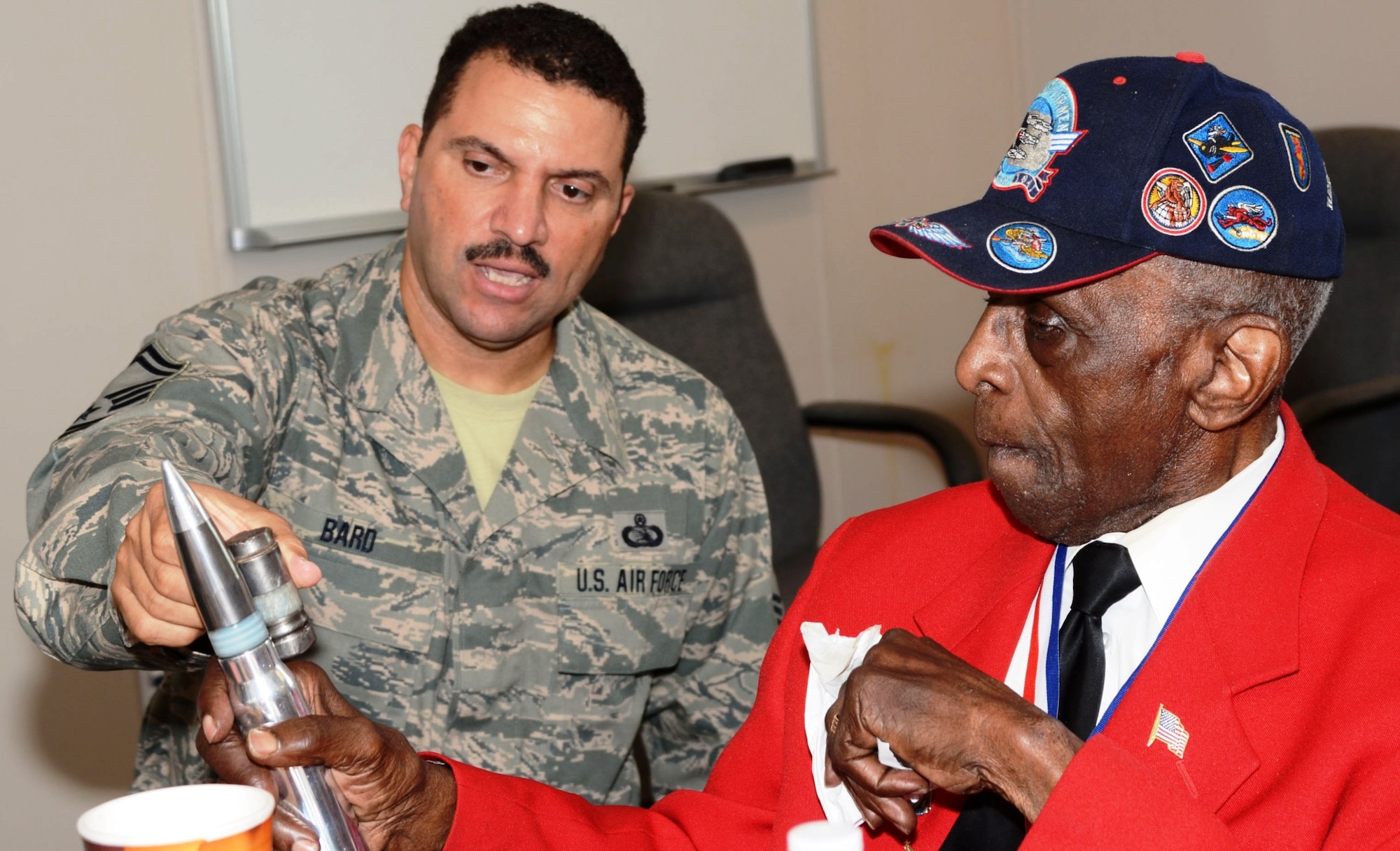 Senior Master Sgt. Ed Bard shows Tuskegee Airman Dr. Cyril O. Byron, Sr. a 30mm round used in the A-10C Thunderbolt II. Byron toured Warfield Air National Guard base on August 11th and talked to members of the Maryland Air National Guard after helping with a promotion ceremony for Bard. (National Guard photo Tech. Sgt. Chris Schepers)