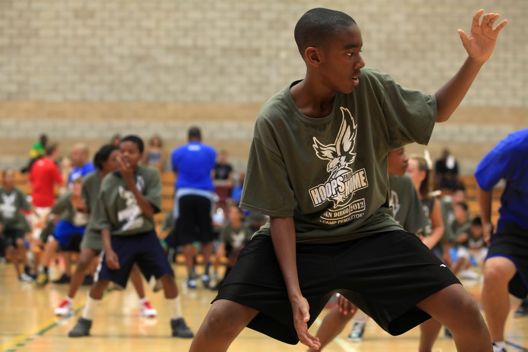 Participants jump into a defensive stance during a warm-up exercise at Camp Pendleton’s Paige Fieldhouse Gymnasium, Aug. 11. Hoops from Home, a non-profit organization, held a basketball training camp to promote healthy, positive development of military children through mentoring from professional and collegian players and coaches.
