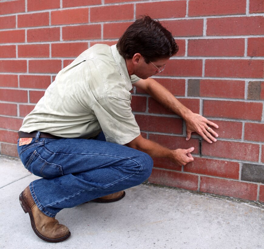 Martin Korenek explaining how exclusion devices work when attached to the wall aboard Marine Corps Base Camp Lejeune Aug. 7. The exclusion devices cause bats roosting in walls the ability to leave the insides of structures but prevent the bats from re-entering.