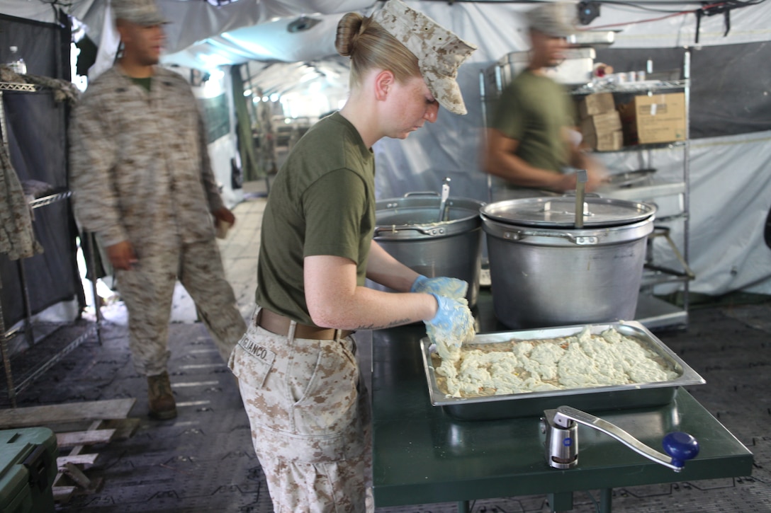 Cpl. Mackenzie Viglianco with 2nd Marine Logistic Group, Combat Logistics Regiment 27’s Food Service Company places biscuit batter atop a tray with chicken a la king as other Marines rush around her to prepare the field mess for the lunch time crowds. Food Service Company was competing for the honor to represent II Marine Expeditionary Force for the Maj. Gen. W.P.T. Hill Award for best field mess Aug. 7.