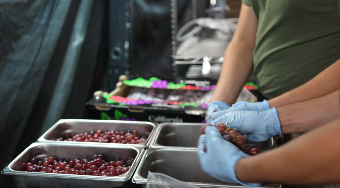 Marines from 2nd Marine Logistic Group, Combat Logistics Regiment 27’s Food Service Company pick grapes apart for a fruit and salad bar during a competition to represent II Marine Expeditionary Force for the Maj. Gen. W.P.T. Hill Award for best field mess Aug. 7. The field mess featured a full fruit and salad bar along with main courses. 