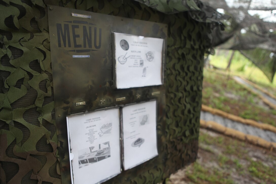 The entry to 2nd Marine Logistic Group, Combat Logistics Regiment 27’s Food Service Company’s field mess hall and galley features a sign displaying the day’s menu. The menu included shrimp Creole and chicken a la king as main courses.
