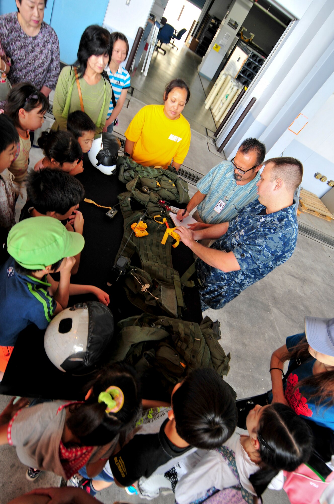 Aircrew Survival Equipmentman 1st Class Brandon Gulley, originally from Pulaski, Tenn. and assigned to Patrol Squadron (VP) 8, displays flight gear that VP-8 pilots wear while flying at Naval Air Facility Misawa, Japan, Aug. 8, 2012. The students, from Shichinohe Community Center, were invited on board NAF Misawa to interact with Sailors and visit several of the base facilities. (U.S. Navy photo by Mass Communication Specialist 2nd Class Kenneth G. Takada/Released)