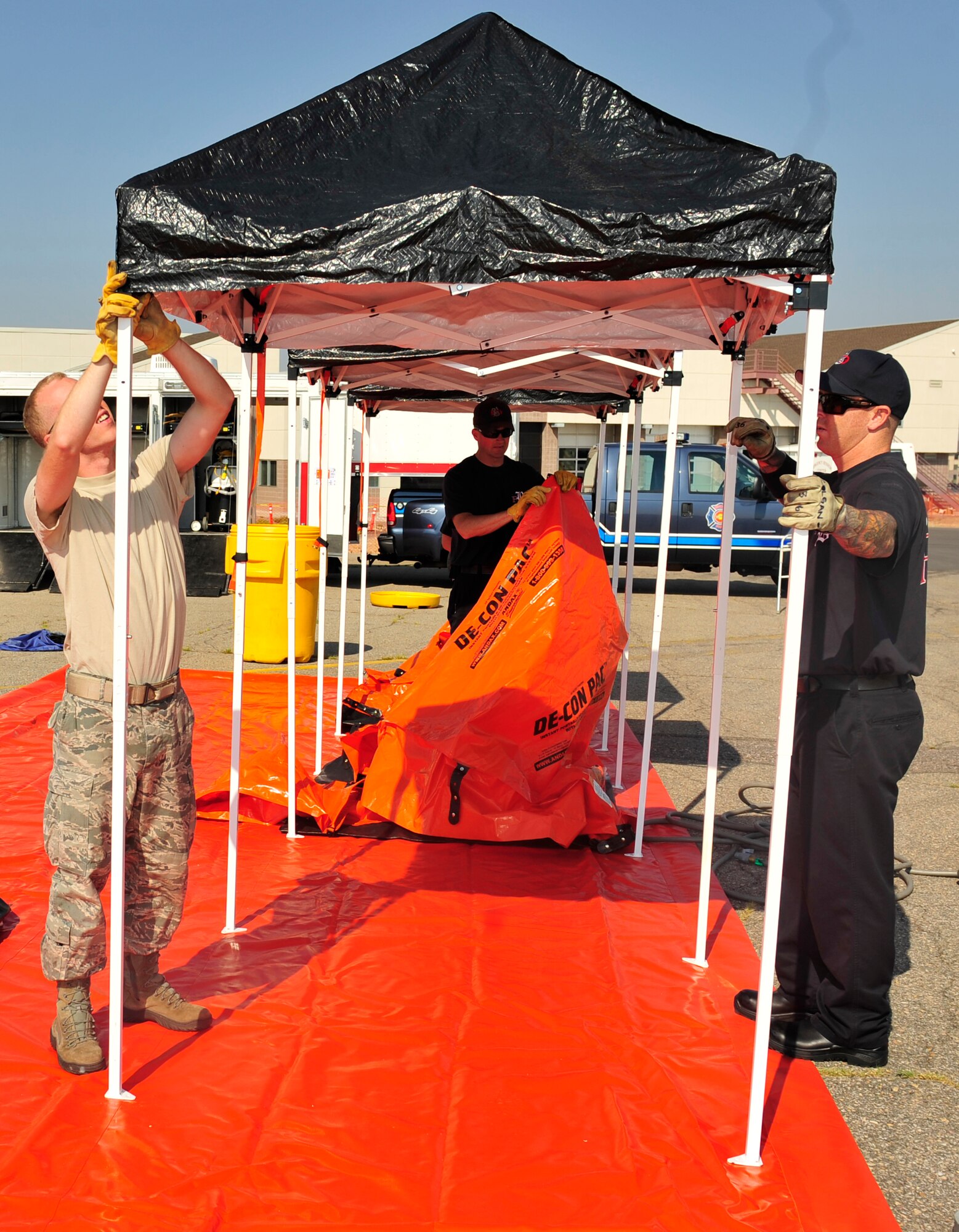 BUCKLEY AIR FORCE BASE, Colo. -- Left to right, Airman 1st Class Allen Patterson, Erik Pingel and Dennis Colgan, all Buckley Fire Department firefighters, wrap up their training after disassembling the training area, Aug.  10, 2012. Buckley firefighters exercise hazardous de-contamination procedures several times a year. (U.S. Air Force photo by Airman 1st Class Darryl Bolden Jr)