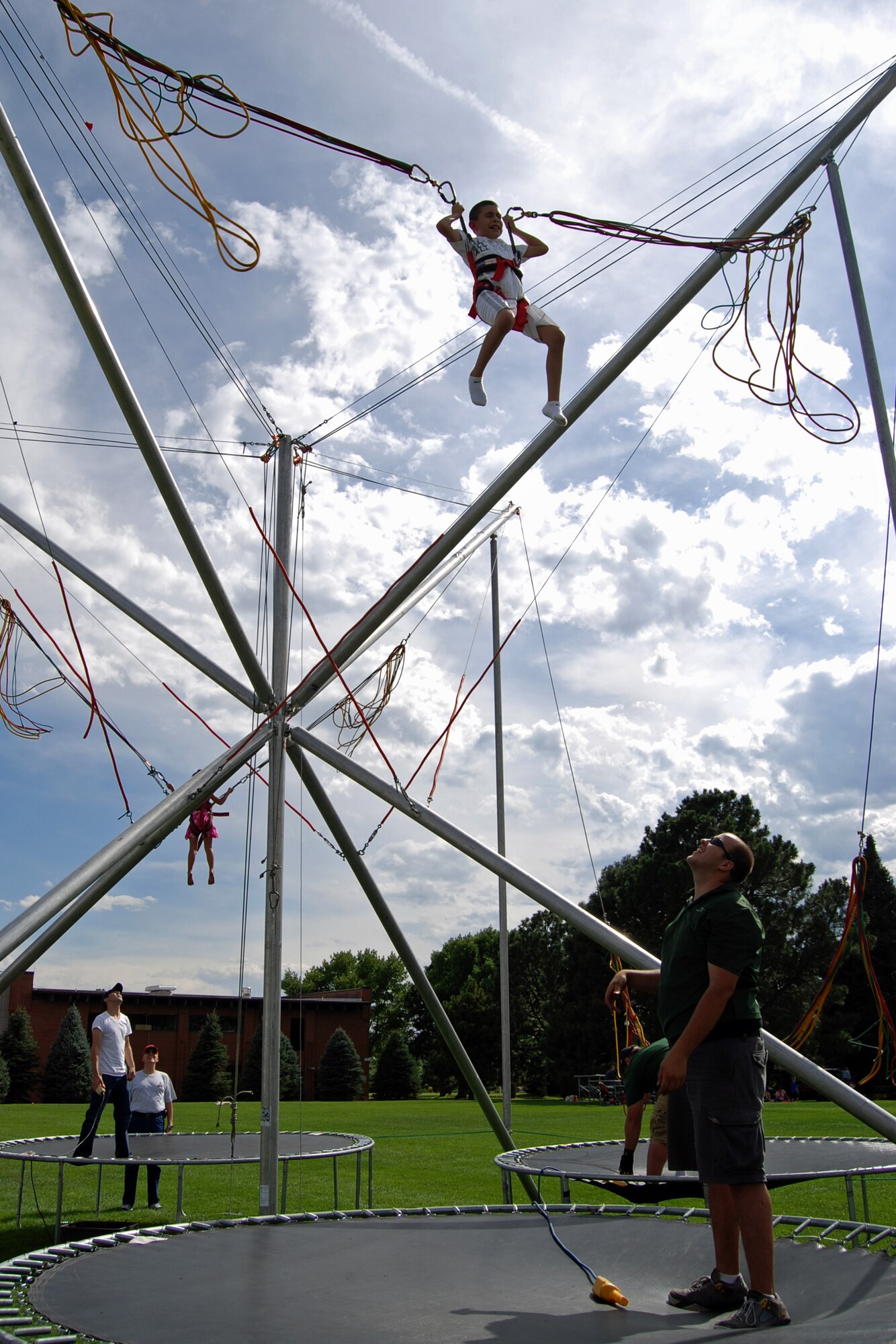 PETERSON AIR FORCE BASE, Colo.—Joe Salazar III, son of Tech. Sgt. Joe Salazar of the 21st Contracting Squadron, flies high on the trampoline swing at the third annual Family Festival and Concert at Patriot Park Aug. 3. The festival featured music, inflatables, a rock climbing wall, and interactive games. Information booths were available for parents regarding resources for families on base and within the community. (U.S. Air Force photo/Lea Johnson)