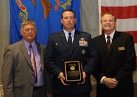 Lynn Stauss, East Grand Forks mayor, and Michael Brown, Grand Forks mayor, present Col. Tim Bush, 319th Air Base Wing commander, with a plaque thanking all the Airmen and civilians at Grand Forks Air Force Base, N.D., for their service in the military and community during a tribute ceremony Aug. 12, 2012.  The ceremony was part of a four-day celebration of the 125th anniversary of the city of East Grand Forks. (U.S. Air Force photo/Senior Airman Amber Bennett)