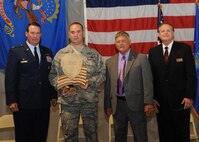 Master Sgt. Clifford Monroe, 319th Civil Engineering Squadron, is presented with an award of recognition, Aug. 12, 2012, by Col. Tim Bush, 319th Air Base Wing commander, alongside Lynn Stauss, East Grand Forks mayor, and Michael Brown, Grand Forks mayor, during a tribute ceremony to honor military, veterans, policemen and firemen at the East Grand Forks Civic Center.  The ceremony was part of a four-day celebration of the 125th anniversary of the city of East Grand Forks.  Monroe was recognized for his actions during a deployment to Afghanistan, where he came under direct and indirect fire more than 35 times. (U.S. Air Force photo/Senior Airman Amber Bennett)