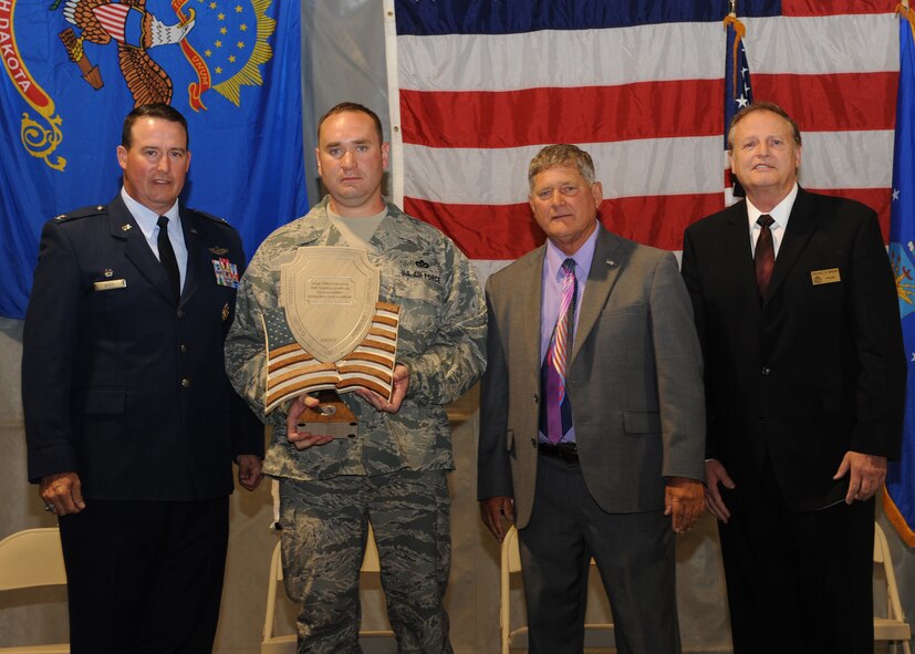 Master Sgt. Clifford Monroe, 319th Civil Engineering Squadron, is presented with an award of recognition, Aug. 12, 2012, by Col. Tim Bush, 319th Air Base Wing commander, alongside Lynn Stauss, East Grand Forks mayor, and Michael Brown, Grand Forks mayor, during a tribute ceremony to honor military, veterans, policemen and firemen at the East Grand Forks Civic Center. The ceremony was part of a four-day celebration of the 125th anniversary of the city of East Grand Forks. Monroe was recognized for his actions during a deployment to Afghanistan, where he came under direct and indirect fire more than 35 times. (U.S. Air Force photo/Senior Airman Amber Bennett) 