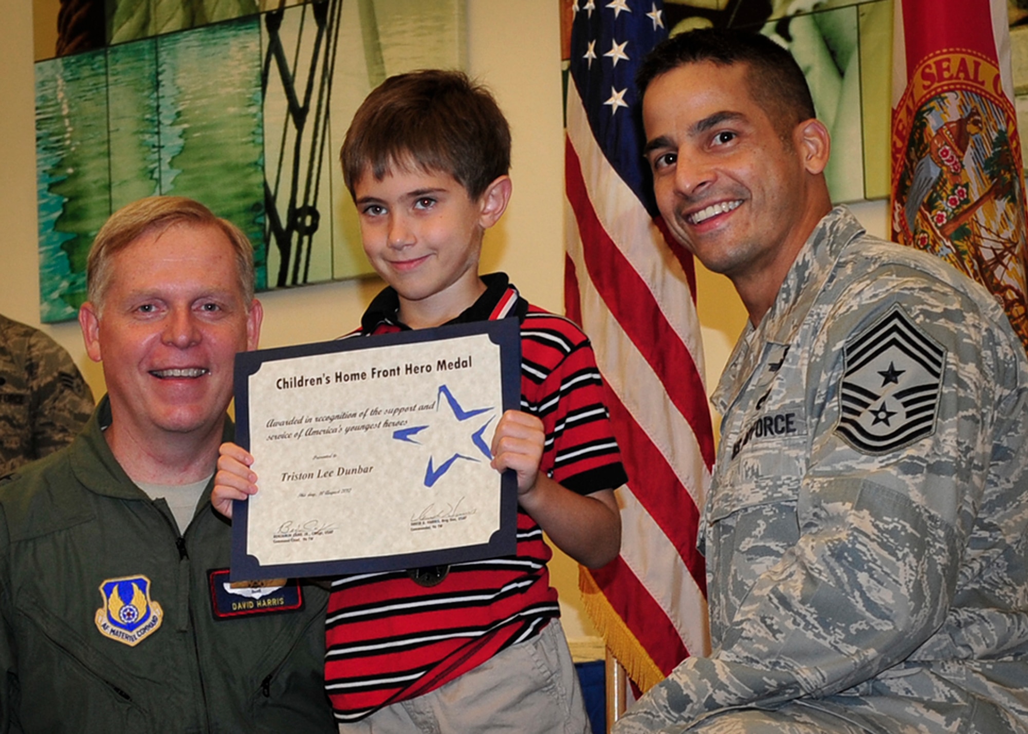 Brig. Gen. David Harris,  the 96th Test Wing commander, and Chief Master Sgt. Ben Caro, the 96th Test Wing command chief, present a certificate of appreciation to Triston Lee Dunbar during the Home Front Heroes ceremony Aug. 10.  Dunbar is the son of Tech. Sgt. Bernadette Fletcher, of the 96th Logistics Readiness Squadron. The event is held to recognize children for their sacrifice and support of their parents’ military service during deployment. (U.S. Air Force photo/Randy Gon)