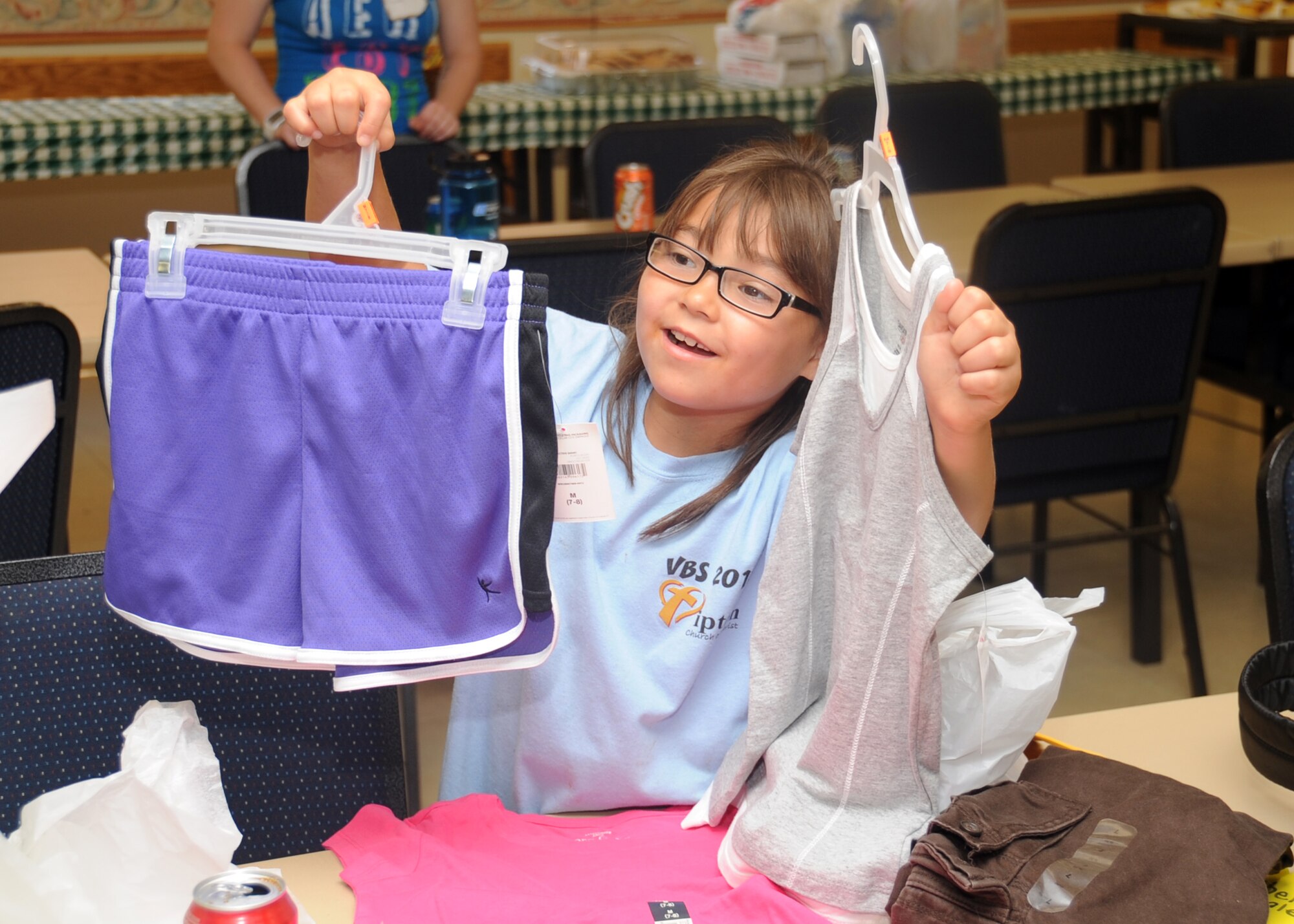 ALTUS AIR FORCE BASE, Okla. – Michelle Booth from the Tipton Children’s Home shows off her clothes at the base chapel during the Christmas in August event Aug. 11, 2012. The children were given clothes and school supplies for the upcoming school year by base personnel. (U.S. Air Force photo by Airman 1st Class Franklin R. Ramos / 97th Air Mobility Wing / Released)