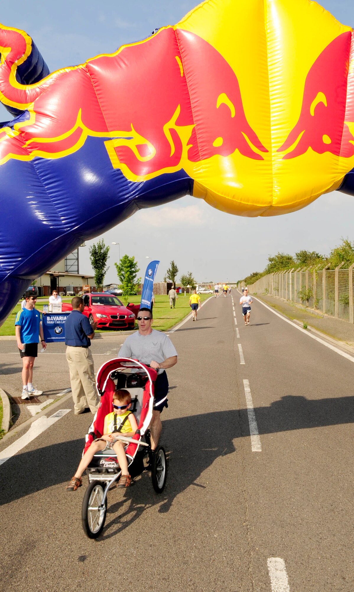 RAF MILDENHALL, England – Jesse Furse, 100th Civil Engineer Squadron, pushes his son Jeremy across the finish line during the Team Mildenhall 5K run at RAF Mildenhall Aug. 10, 2012. The run is a monthly event that helps to build morale and fitness through healthy competition. (U.S. Air Force photo/Senior Airman Ethan Morgan)