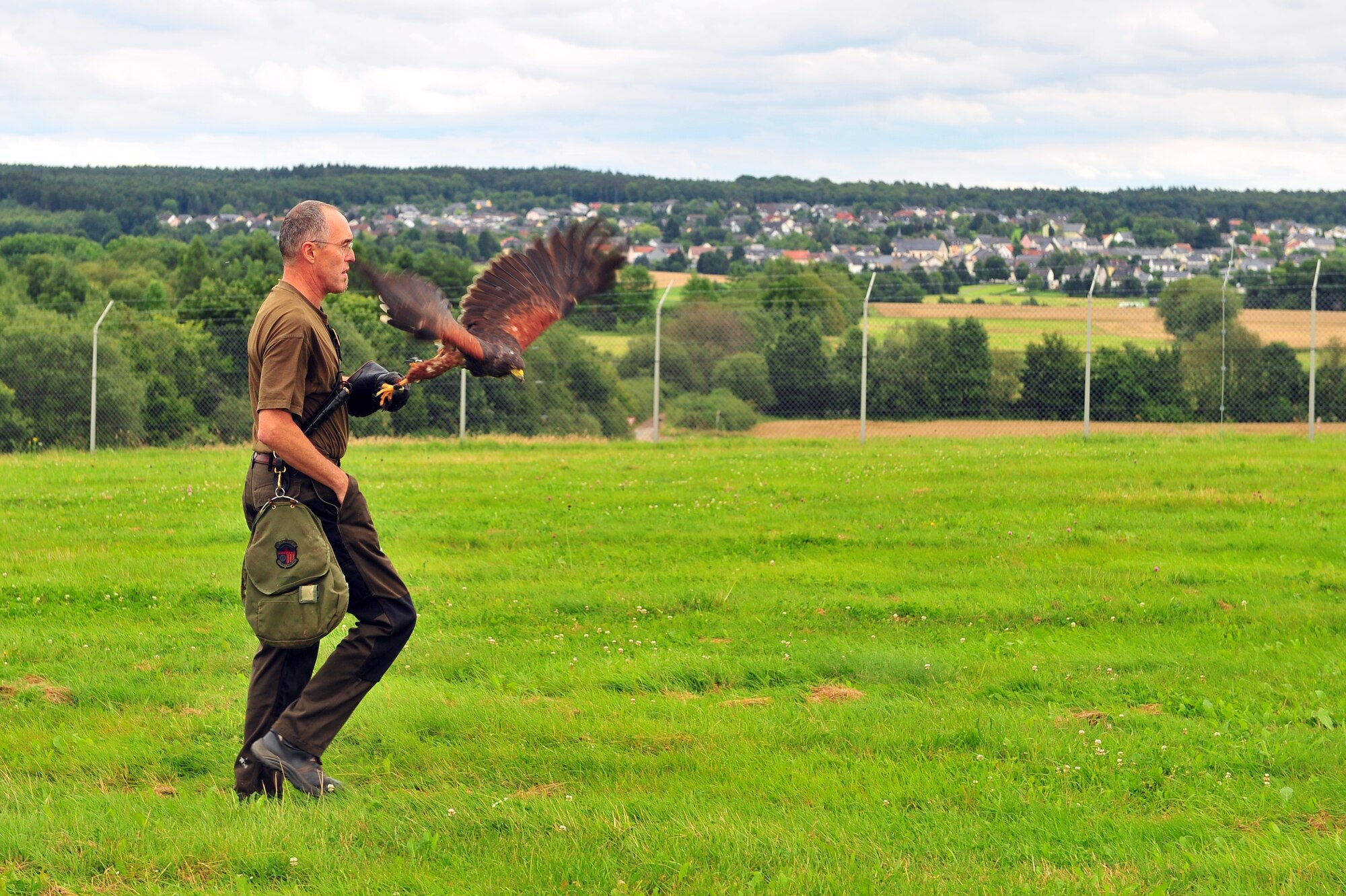 SPANGDAHLEM AIR BASE, Germany – Roland Leu, 52nd Fighter Wing falconer, patrols the fields near Perimeter Road for rabbits July 31. Leu is the wing’s only falconer and he uses his four falcons to hunt birds and rodents throughout the year. The falconer keeps rodent and bird populations clear of aircraft and helps reduce the amount of damage and cost of repairs done to aircraft. (U.S. Air Force photo by Airman 1st Class Dillon Davis/Released)