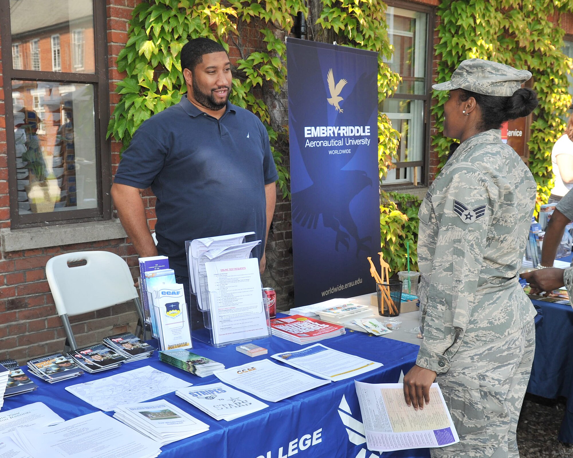 RAF MILDENHALL, England – Tarrell Matthews, 100th Force Support Squadron, speaks to Senior Airman Santianna White, 100th FSS, about the Community College of the Air Force during the college fair and barbecue Aug. 10, 2012, in Washington Square. The fair featured information tables from colleges offering classes on base and at RAF Lakenheath as well as a barbecue and family activities available to all Airmen on base. (U.S. Air Force photo/Senior Airman Jerilyn Quintanilla)