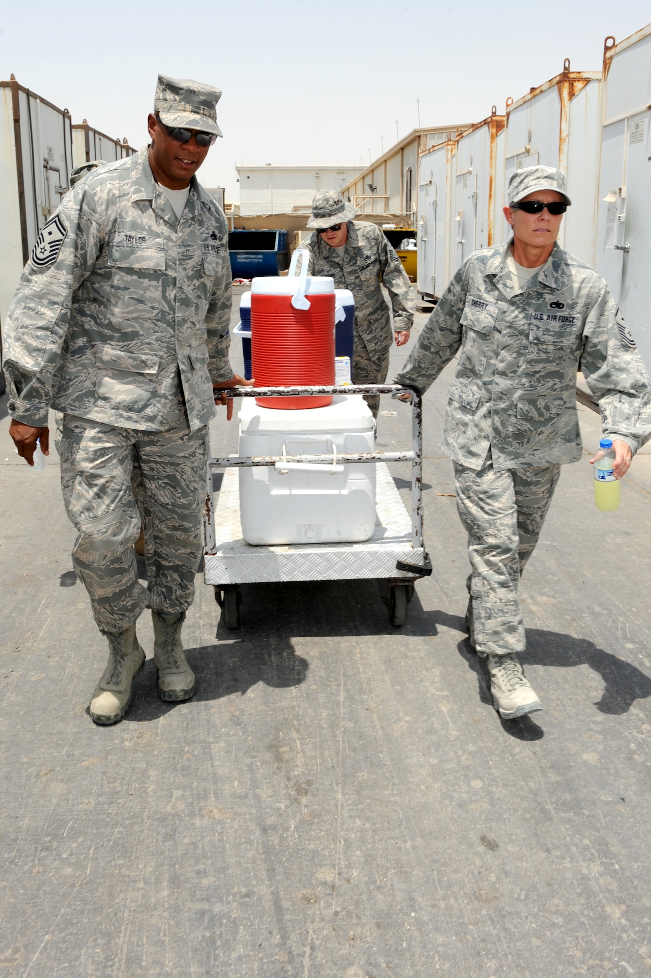 SOUTHWEST ASIA - U.S. Air Force Senior Master Sgt. Edward Taylor III, 380th Expeditionary Mission Support Group first sergeant, and Master Sgt. Laurie Cherry, 727th Expeditionary Air Control Squadron first sergeant, haul a cart full of refreshments Aug. 10, 2012. The 380th Air Expeditionary Wing's first sergeants and chaplains periodically get together to hand out refreshments to Airmen working outside in the heat. (U.S. Air Force photo/Master Sgt. Scott MacKay)
