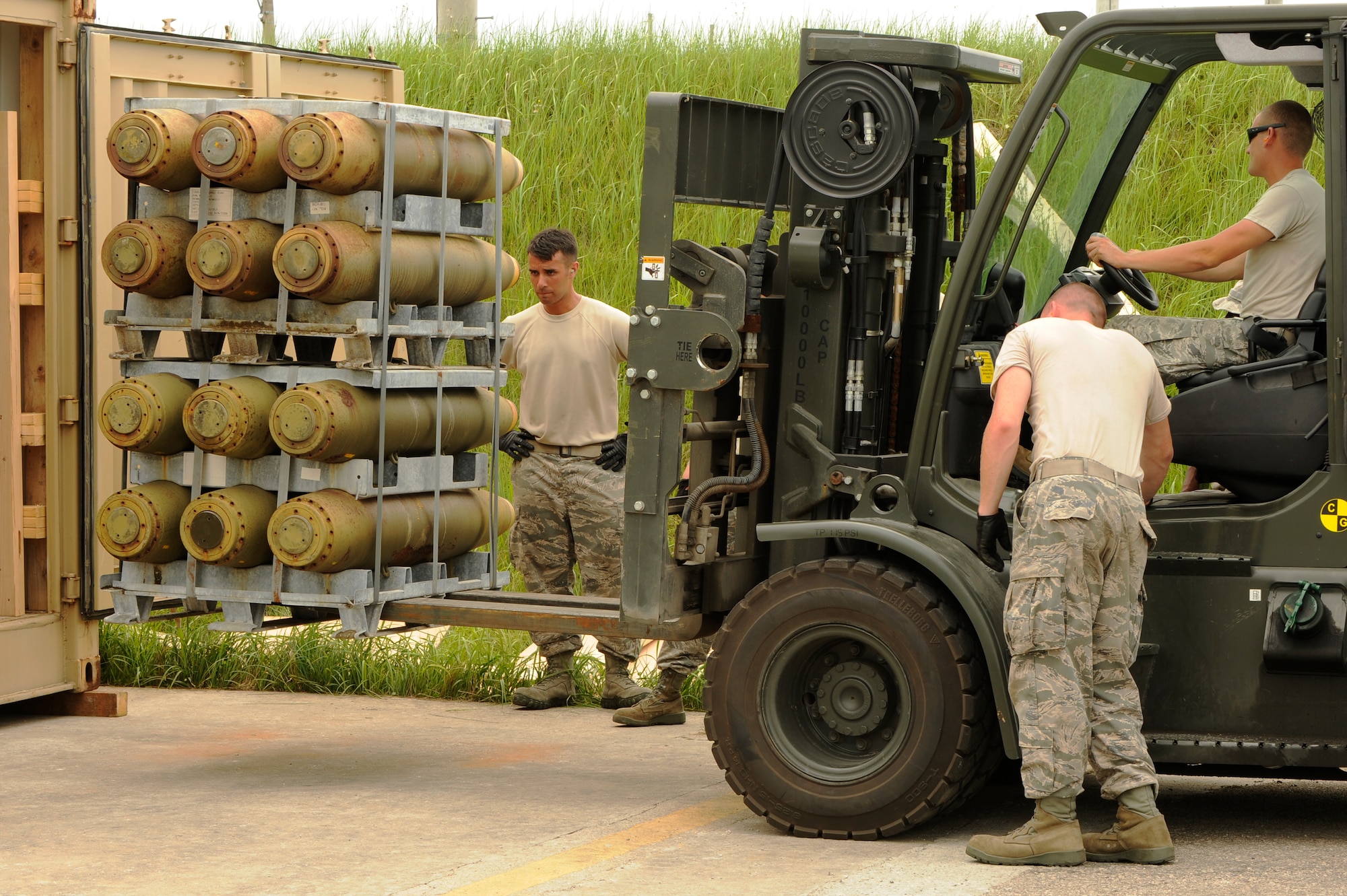 Airman 1st Class Manuel Fralick, left, with the 51st Logistics Readiness Squadron at Osan Air Base, Republic of Korea, and Senior Airman Jason Becker, 8th Maintenance Squadron ammo, assist Senior Airman Justin Salinas, 8th MXS ammo, as he loads old munitions into a shipping container at Kunsan Air Base, Aug. 2, 2012. The 3 million pounds of ammo being shipped is worth $94 million. (U.S. Air Force photo/Senior Airman Marcus Morris)