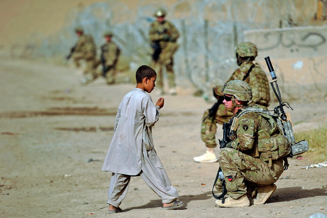 U.S. Army Sgt. Brian Reid talks with an Afghan child during a dismounted patrol in Afghanistan's Kandahar province, Aug. 8, 2012. Reid is assigned to the Kandahar Provincial Reconstruction Team.