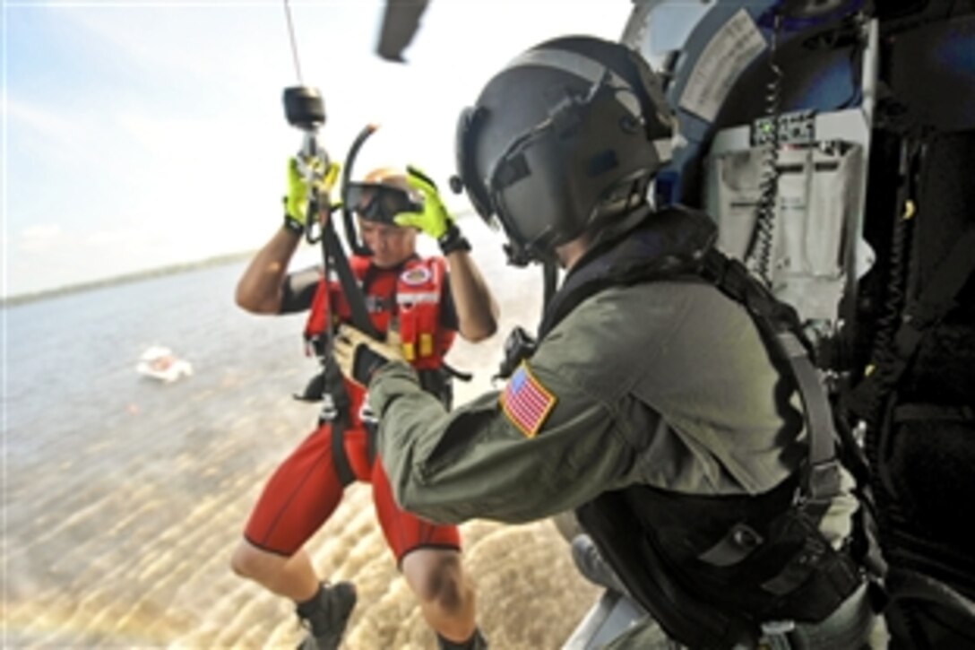 Coast Guard Petty Officer 2nd Class Jonathan Avery lowers Petty Officer 1st Class Bret Fogle into the Pasquotank River near Coast Guard Air Station Elizabeth City, N.C., Aug. 3, 2012. The crews conducted hoist training with cadets from the Coast Guard Academy in New London, Conn., as part of their summer visit to the air station. Avery, a flight mechanic, and Fogle, a rescue swimmer, are assigned to the North Carolina station.