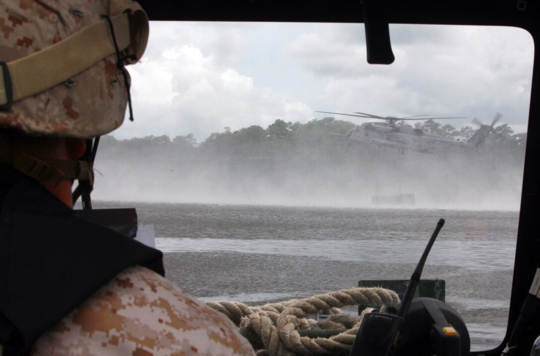 Sgt. Jonathon Krauss, a combat engineer with 8th Engineer Support Battalion, 2nd Marine Logistics Group, watches a CH-53 Super Stallion drop a section of an improved ribbon bridge into the water aboard Camp Lejeune, N.C., Aug. 8, 2012. During the exercise, the helicopter lowered parts of a raft into the water as Marines waited near the shore. The Marines raced to the individual sections floating in the bay to open and secure them after the raft was in the water. (U.S. Marine Corps photo by Pvt. Franklin E. Mercado)