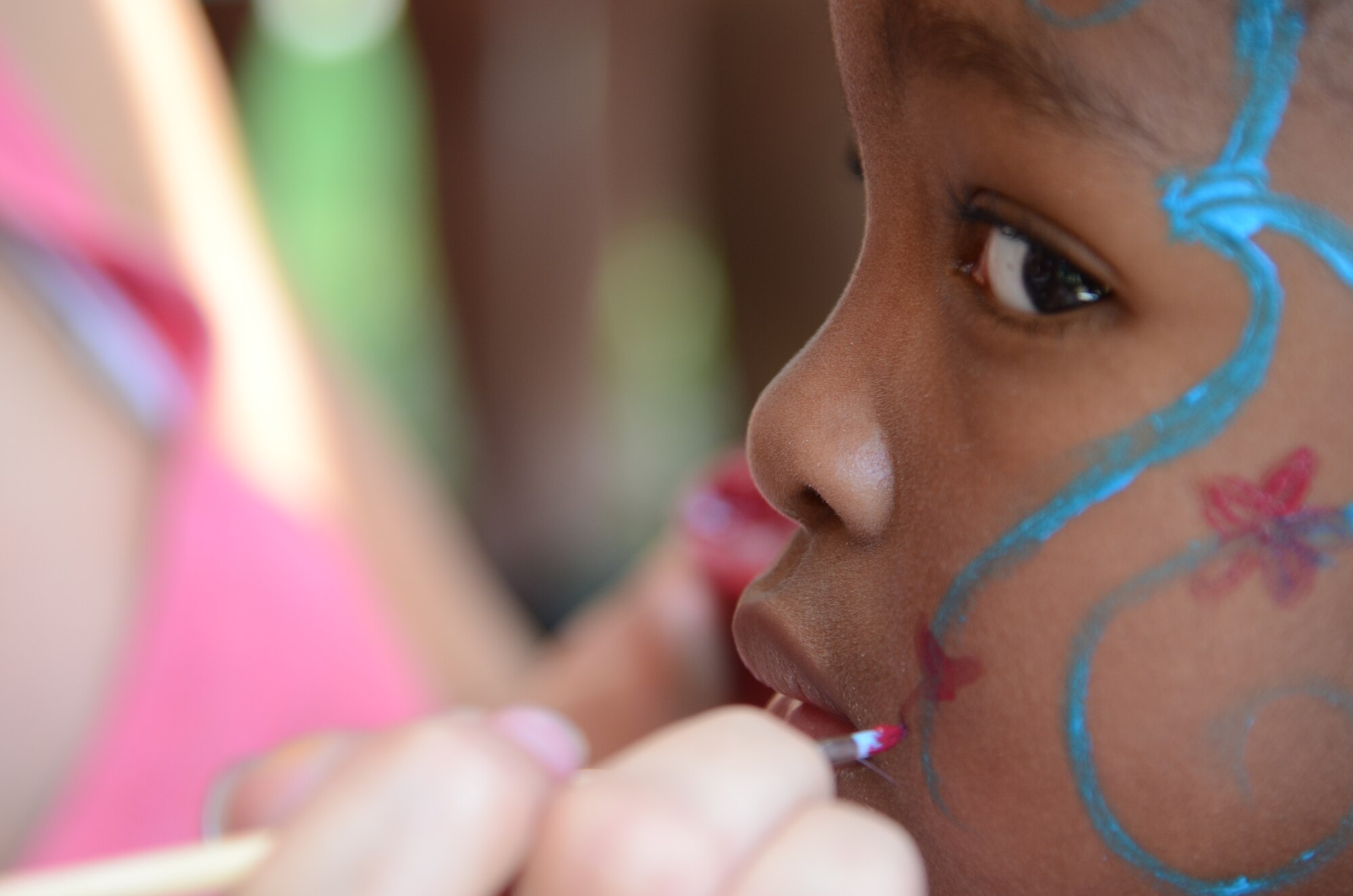 SHAW AIR FORCE BASE, S.C. - Gabrielle Scott looks around as U.S. Air Force Senior Airman Lindsey Antonovich, an air traffic controller assigned to the 20th Operations Support Squadron paints her face during the Summer Splash event in the Woodland Pool area of Shaw Air Force Base, S.C., Aug. 13, 2012. More than 1,200 members of Team Shaw participated in the event that was sponsored by the city of Sumter, S.C., Farmer's Telephone Cooperative, Progress Energy and 20th Fighter Wing members.  Attendees were treated to free food, face painting, water games, music and snow cones. (U.S.  Air Force photo by Master Sgt. Cohen A. Young/Released)