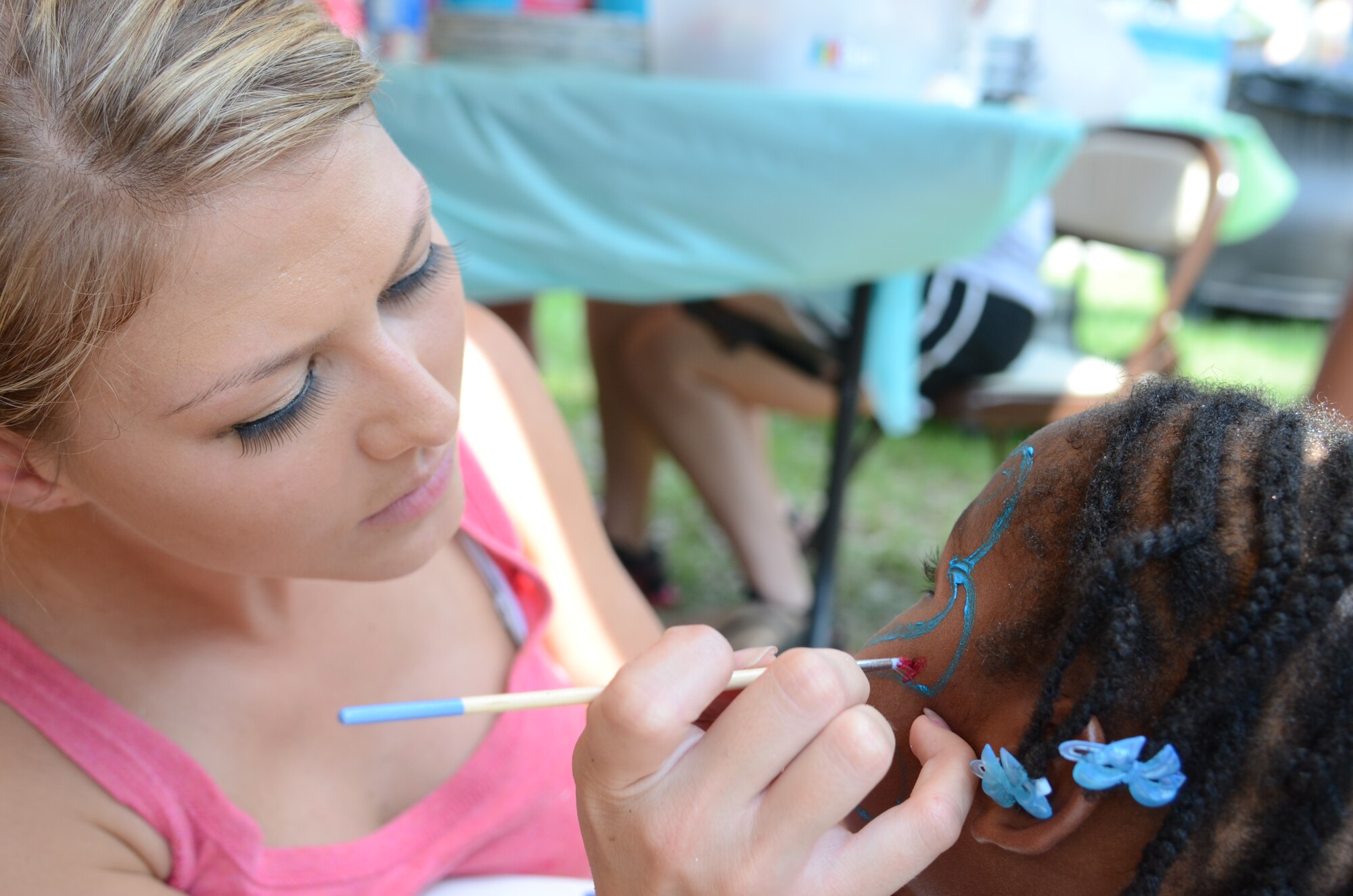 SHAW AIR FORCE BASE, S.C. - U.S. Air Force Senior Airman Lindsey Antonovich, an air traffic controller assigned to the 20th Operations Support Squadron displays her creative ability while painting the face of Gabrielle Scott during the Summer Splash event in the Woodland Pool area of Shaw Air Force Base, S.C., Aug. 13, 2012. More than 1,200 members of Team Shaw participated in the event that was sponsored by the city of Sumter, S.C., Farmer's Telephone Cooperative, Progress Energy and 20th Fighter Wing members.  (U.S.  Air Force photo by Master Sgt. Cohen A. Young/Released)