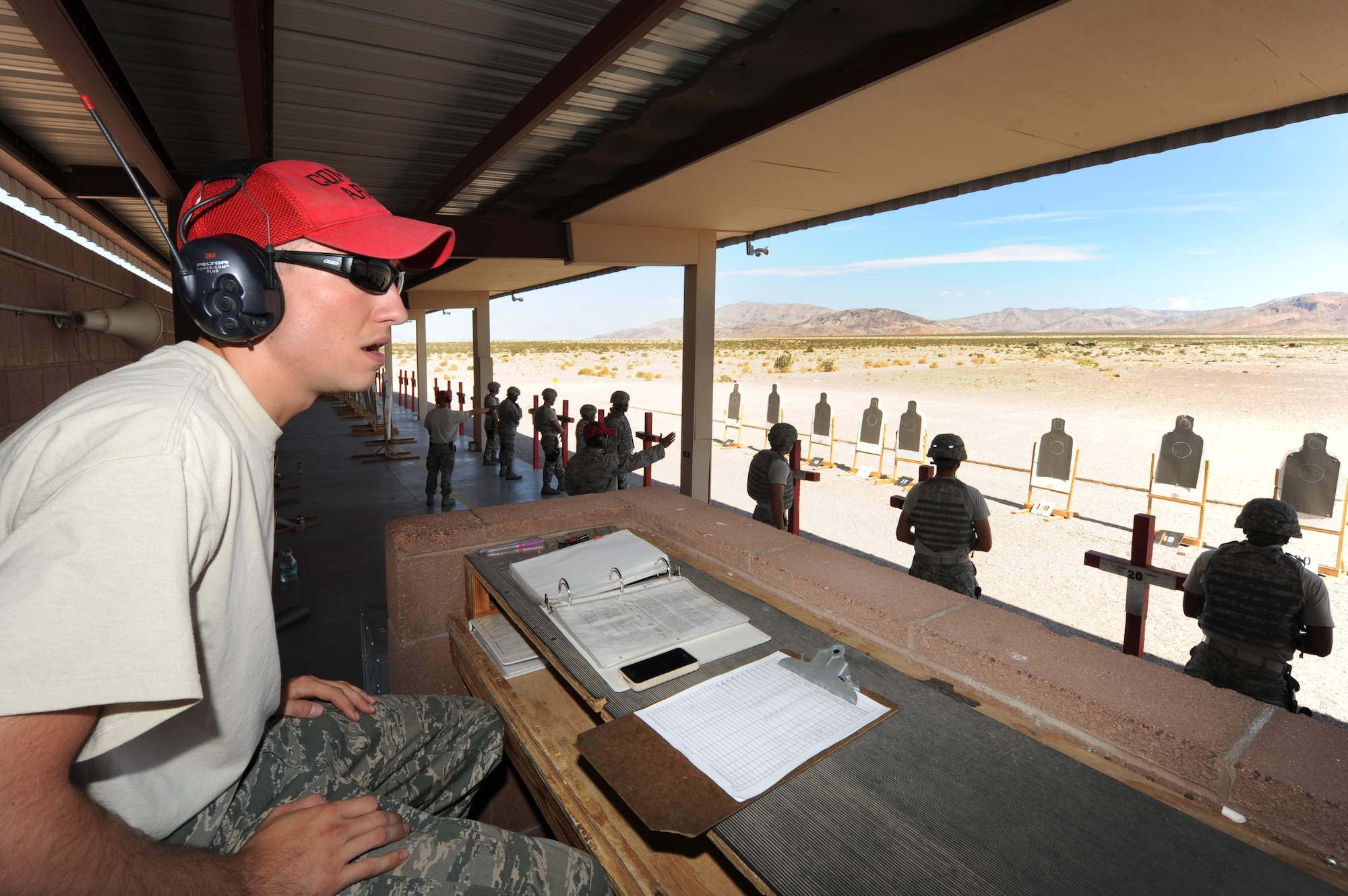 Senior Airman Jonathan Owens, 99th Security Forces Squadron combat arms instructor, commands the firing line during M9 Beretta pistol  qualification training Aug. 13, 2012, at Nellis Air Force Base, Nev. Owens and other combat arms instructors keep the firing range safe while helping Airmen improve their shooing skills. (U.S. Air Force photo by Staff Sgt. William P.Coleman)
  

