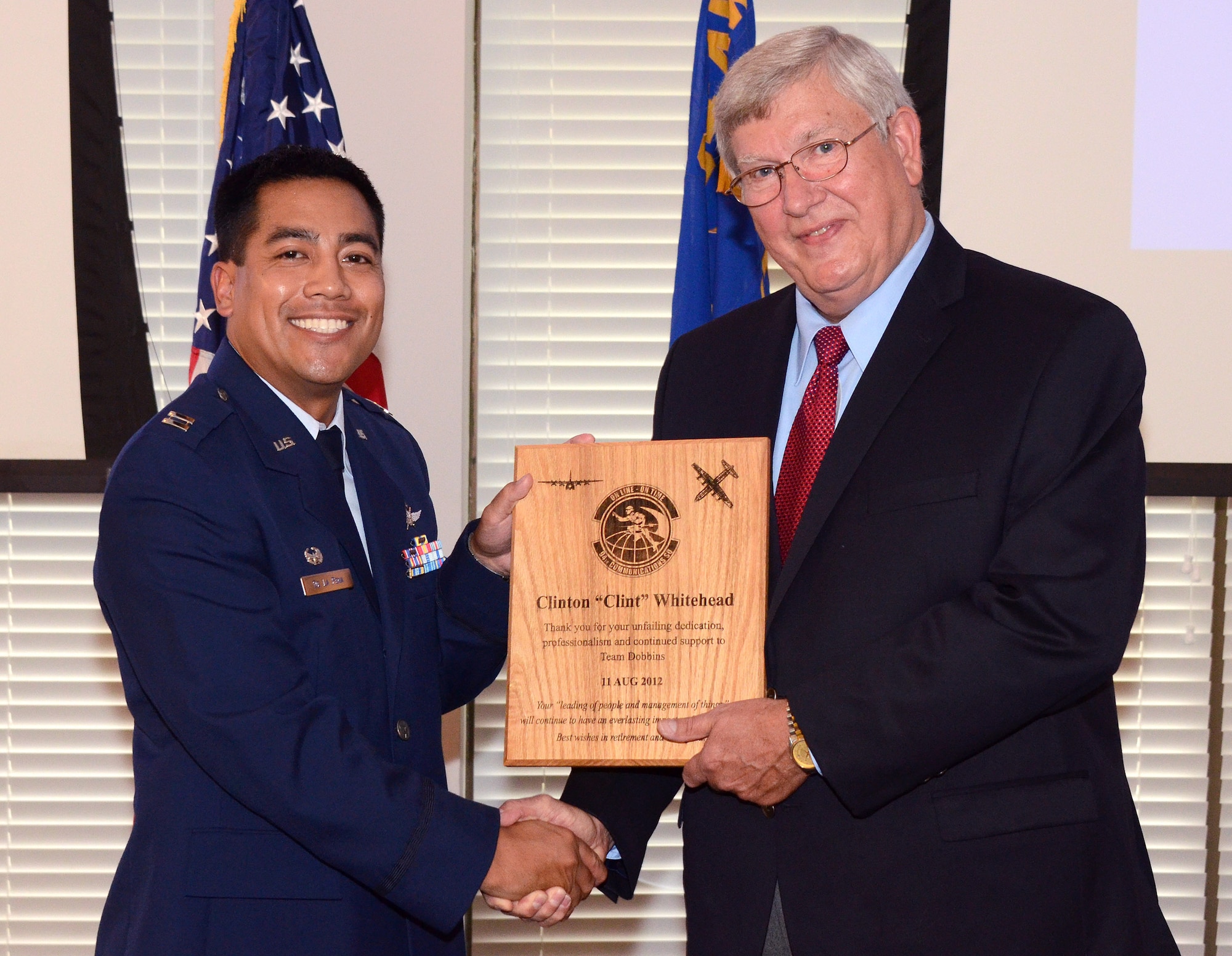 Capt. Jamison De La Pena, 94th Communications Squadron commander, presents Clint Whitehead with a plaque during his retirement ceremony at Dobbins Air Reserve Base, Aug. 9. Clint Whitehead is retiring from the 94th Communications Squadron as the communications manager after 43 years of combined military and federal service.  (U.S. Air Force photo/Brad Fallin)