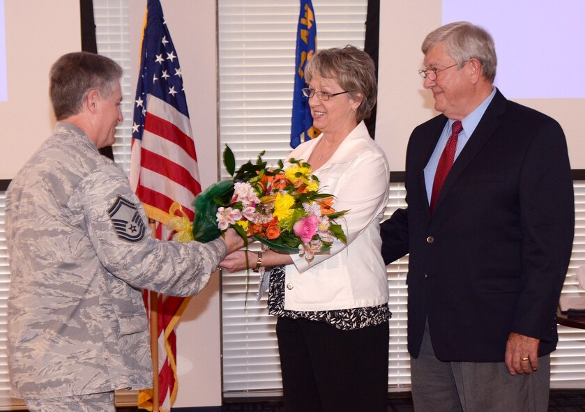 Senior Master Sgt. Tommy Sams presents Katherine Whitehead with a bouquet of flowers to honor her support of Clint Whitehead throughout his career here at Dobbins Air Reserve Base, Aug. 9. Clint Whitehead is retiring from the 94th Communications Squadron as the communications manager after 43 years of combined military and federal service.  (U.S. Air Force photo/Brad Fallin)