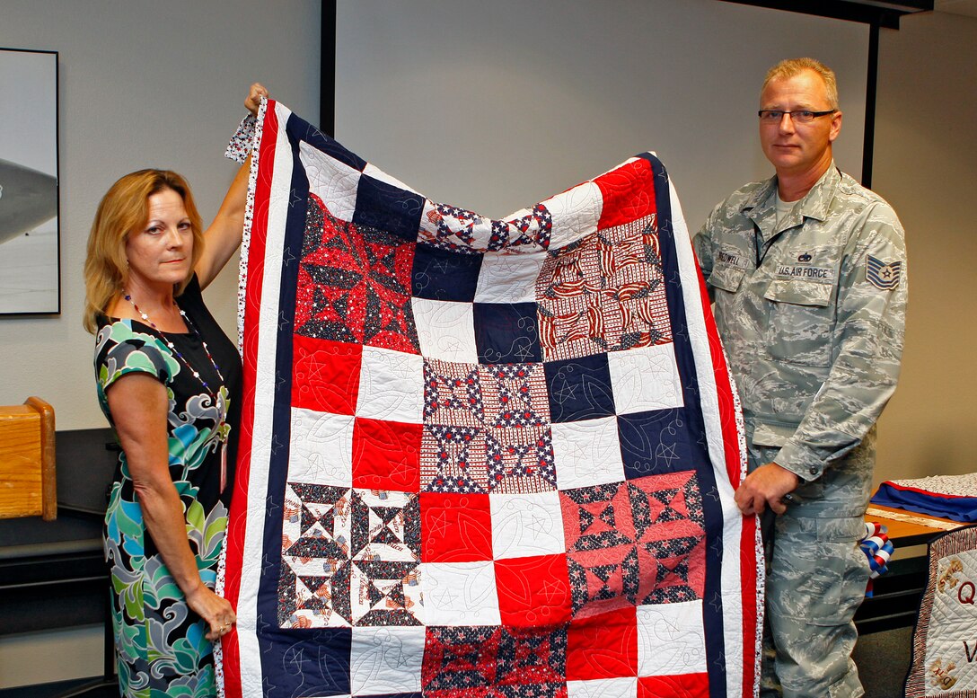 Katherine Trowbridge, Air Force Test Center Contracting Directorate resource advisor, presents Tech. Sgt. Lawrence Bredwell, 31st Test and Evaluation Squadron fighter aircraft crew chief, with a Quilt of Valor during a presentation ceremony in Building 2800 on Aug. 8. (U.S. Air Force photo by Jet Fabara)