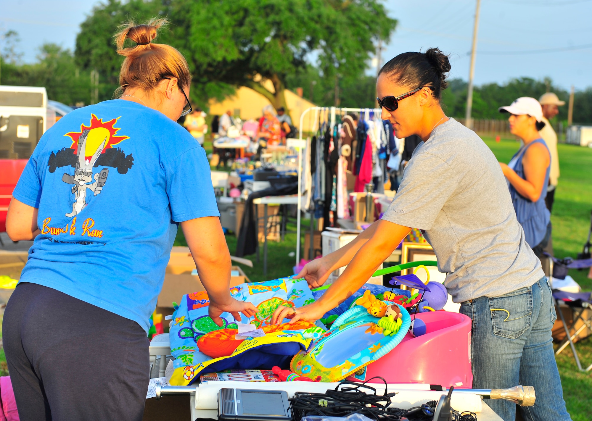 U.S. Air Force Staff Sgt. Stephani Fallis, 20th Fighter Wing Legal Office NCO of non-judicial punishment, shows a customer an infant play mat on Shaw Air Force Base, S.C., Aug. 11, 2012. The Community Activity Center (CAC) sponsored a base wide yard sale allowing all Department of Defense card holders to purchase tables and sell items to the Sumter community. The money that the CAC raised will go towards programs for the Shaw community. (U.S. Air Force photo by Senior Airman Amber E. N. Jacobs/Released)

