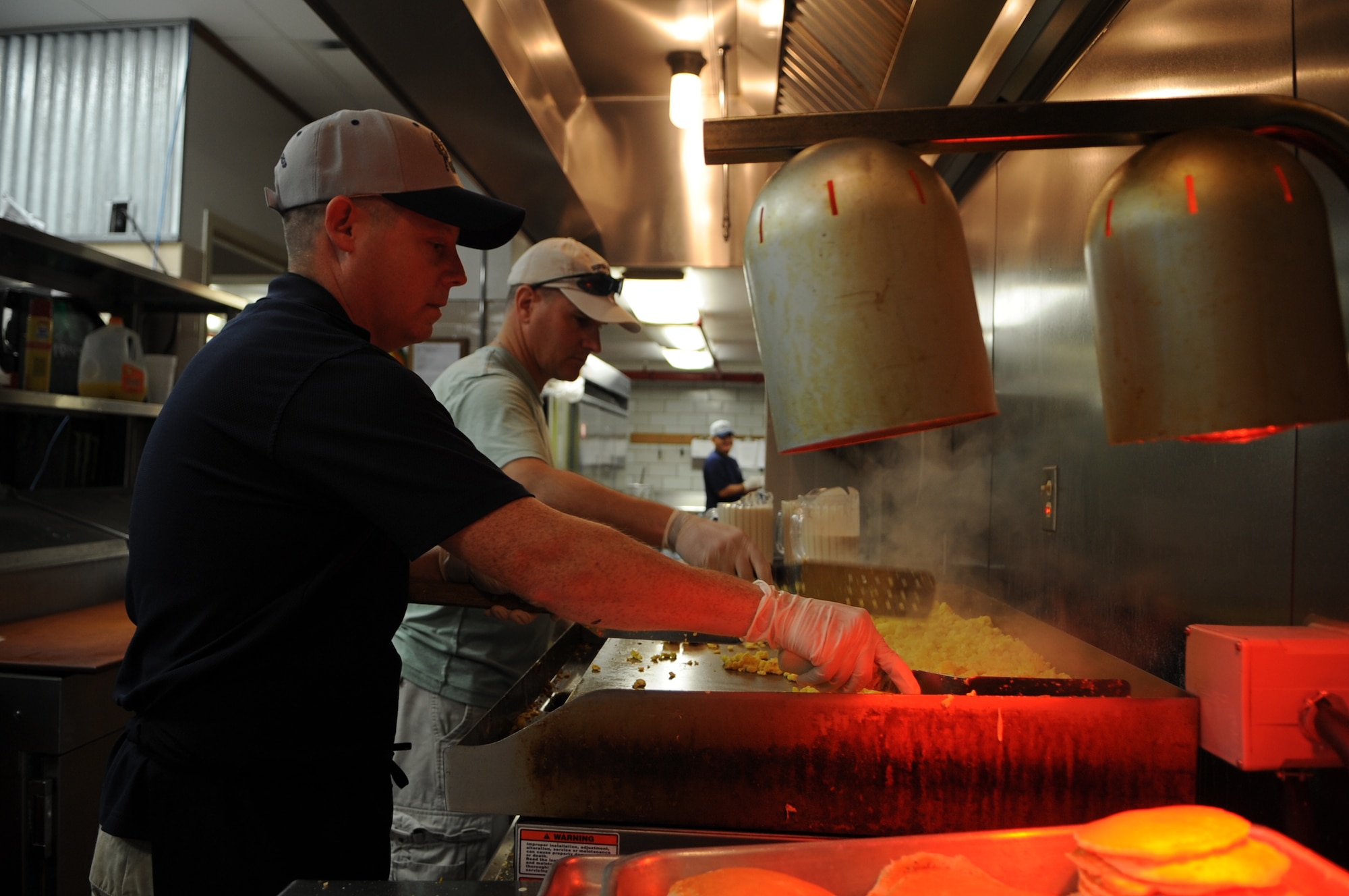 U.S. Air Force Chief Master Sgts. Scott Stevenson, 4th Operations Support Squadron chief controller at radar approach and control, and Thom Trottier, 4th Medical Group superintendent, cook eggs during a Chief’s Group pancake breakfast on Seymour Johnson Air Force Base, N.C., Aug. 10, 2012. Airmen and family members were offered a selection of scrambled eggs, sausage, orange juice, coffee and unlimited pancakes. (U.S. Air Force photo/Airman 1st Class Aubrey Robinson/Released)