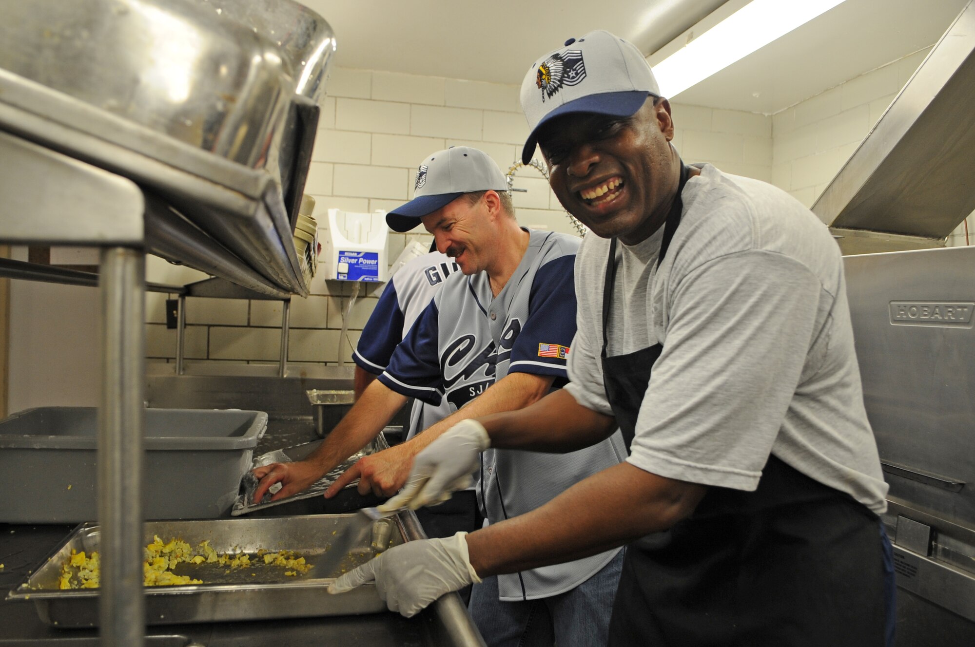 U.S. Air Force Chief Master Sgts. Scott Lilly, 414th Maintenance Squadron maintenance superintendent, and Reuben Abraham, 4th Maintenance Operations Squadron superintendent, share a laugh as they work the kitchen during a Chief’s Group pancake breakfast on Seymour Johnson Air Force Base, N.C., Aug. 10, 2012. All cooking and clean-up duties during the breakfast were handled by members of the Chief’s Group. (U.S. Air Force photo/Airman 1st Class Aubrey Robinson/Released)