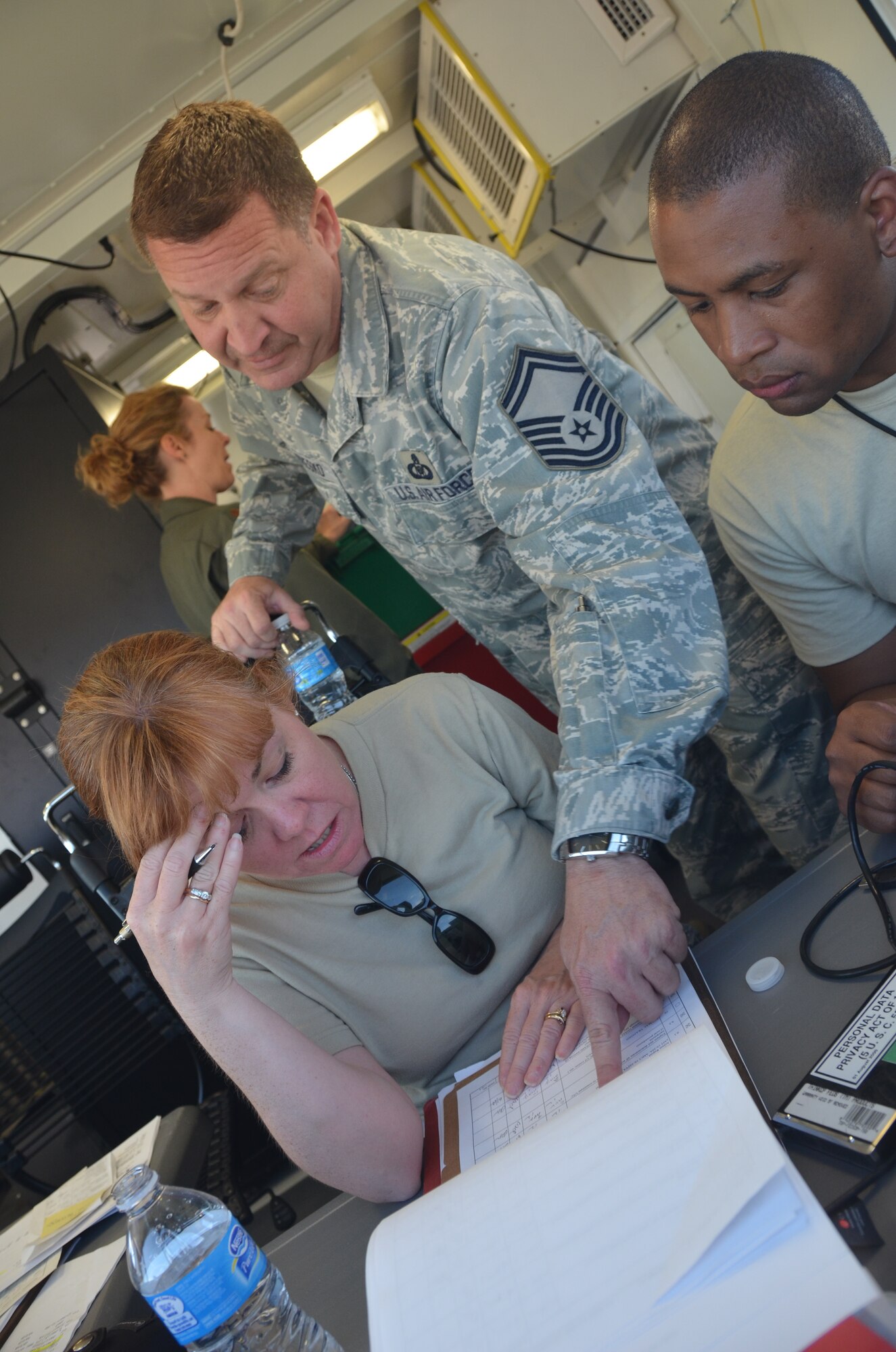 Inside the Hard-sided Expandable Lightweight Air Mobility Shelter (HELAMS), SMSgt. Paul Veresko and SSgt. Kennether Kerr show SSgt. Winnie Dion, all three members of the 439th Airlift Control Flight, the importance of written records and how to track progress of checklists imperitive to the ALCF mission in Colorado Springs during Patriot Express Exerise on August 11, 2012. (U.S. Air Force photo by SrA. Kelly Galloway)
