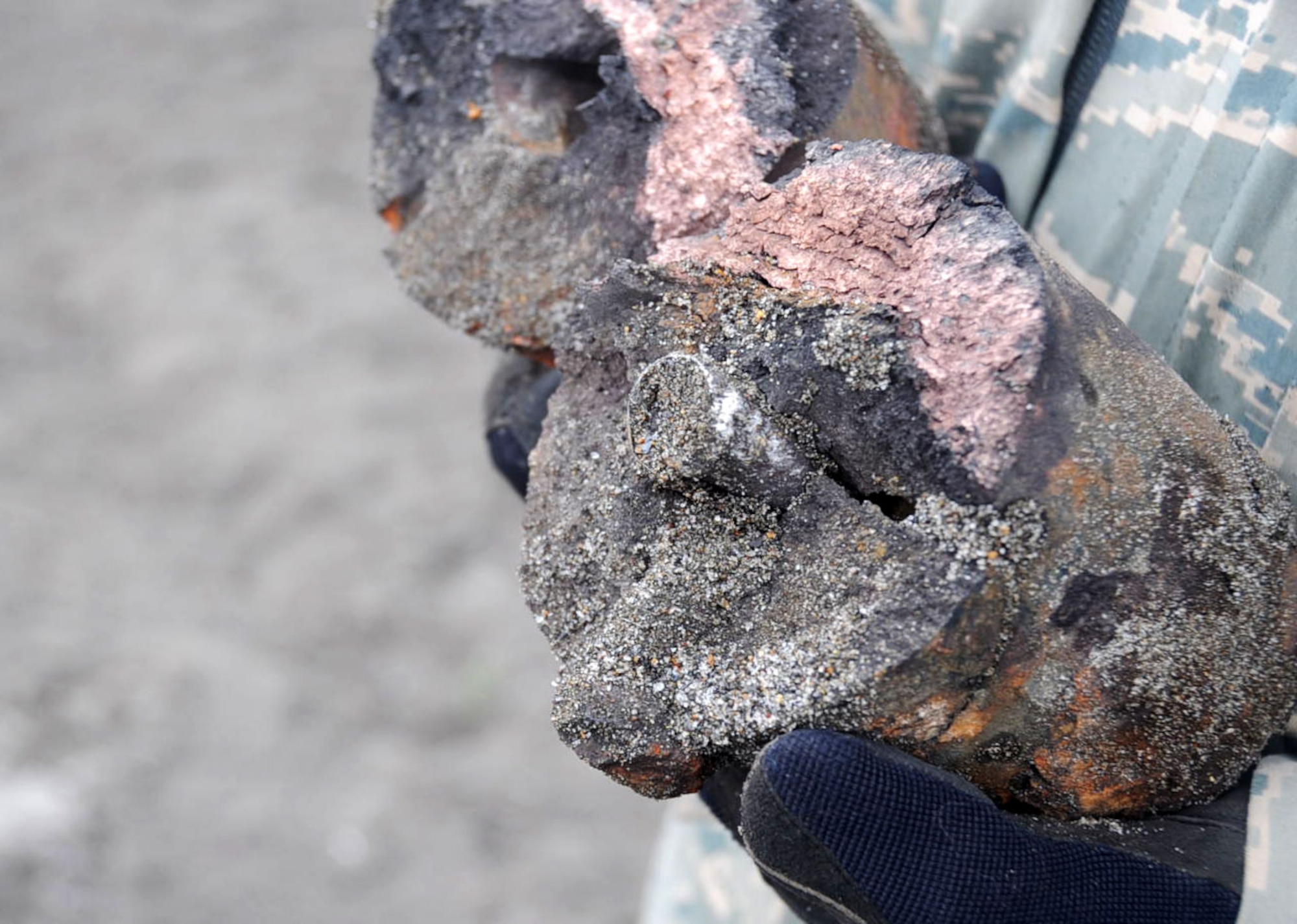 A U.S. Air Force 35th Civil Engineer Squadron explosive ordnance disposal Airman holds a destroyed dud explosive at Daughn Range in Misawa, Japan, Aug. 13, 2012. When the core is split in two, it means the explosive is no longer dangerous. (U.S. Air Force photo by Airman 1st Class Kenna Jackson/Released)