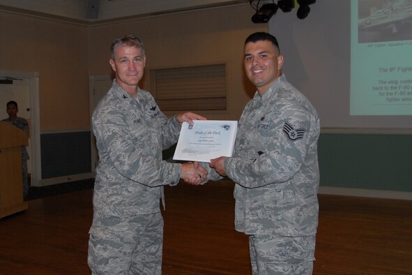Col. John Pearse, 8th Fighter Wing commander, presents Staff Sgt. Brian Lopez, 8th Security Forces Squadron, with a Pride of the Pack award Aug. 9, 2012.  Pride of the Pack recognized the outstanding work Wolf Pack Airmen do everyday. (U.S. Air Force photo/Capt. Sheila Johnston)
